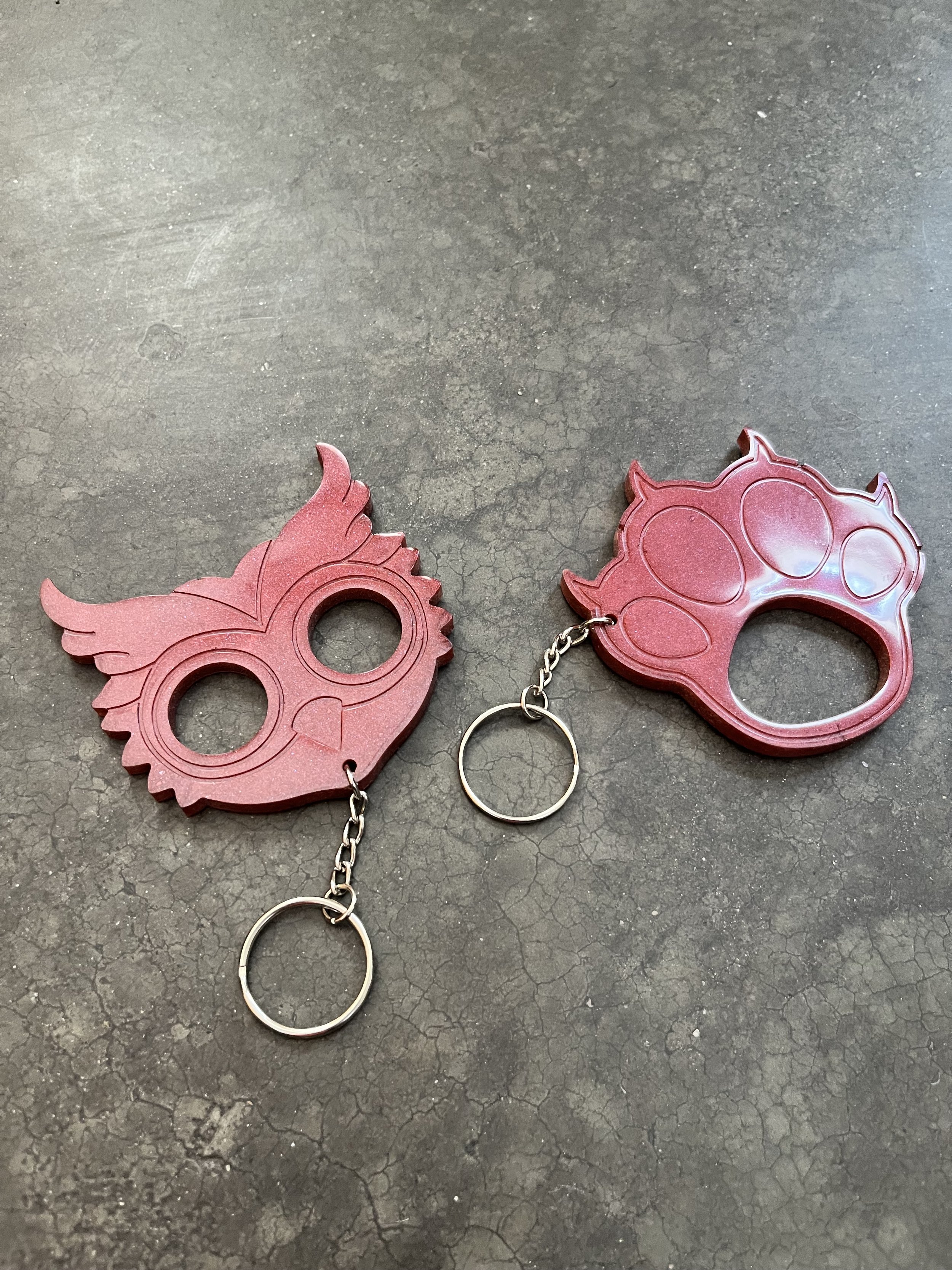 Two resin epoxy emergency keychains, placed on a cracked dark gray surface.