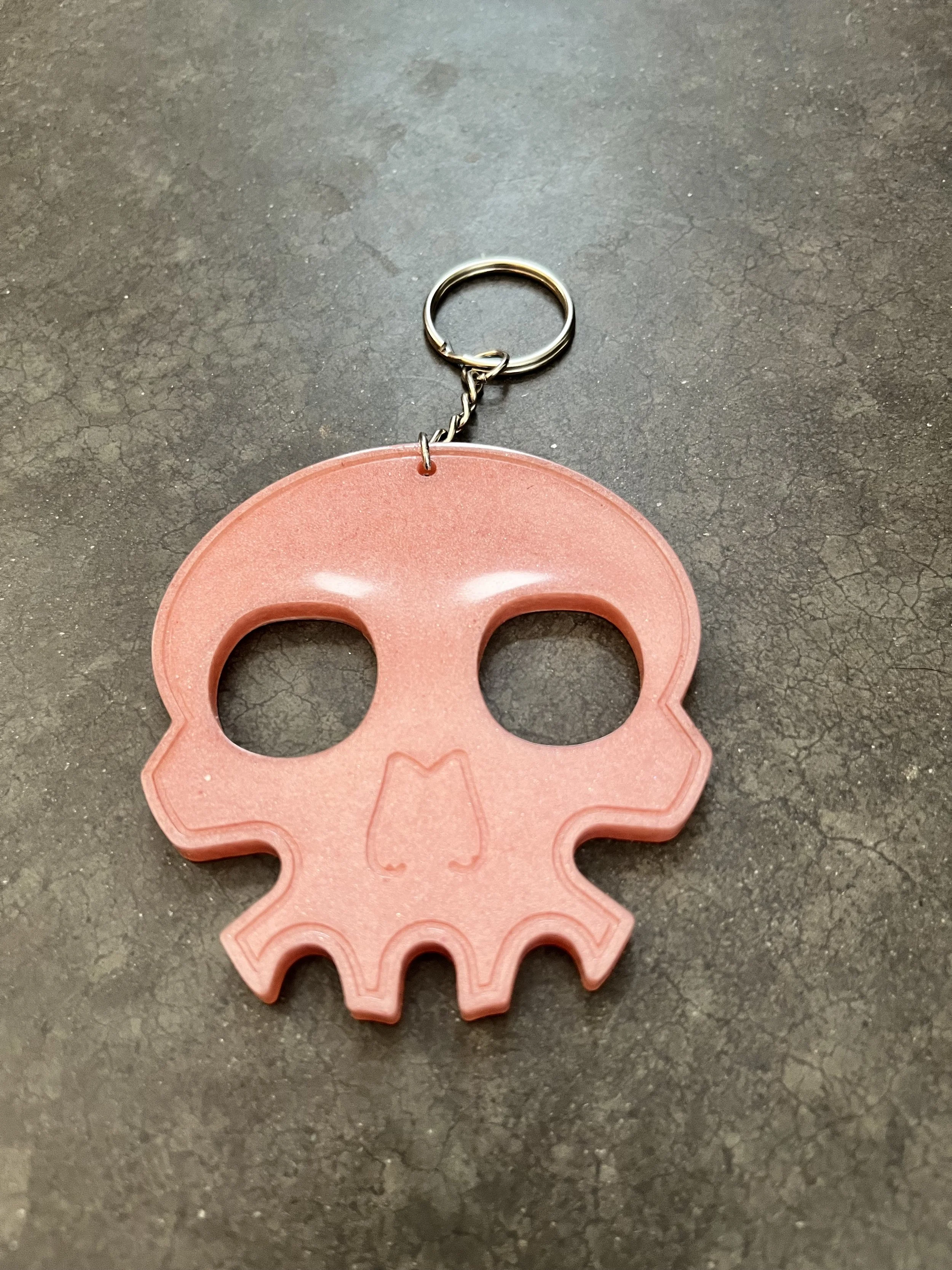 A handmade orange skull resin epoxy emergency keychain.