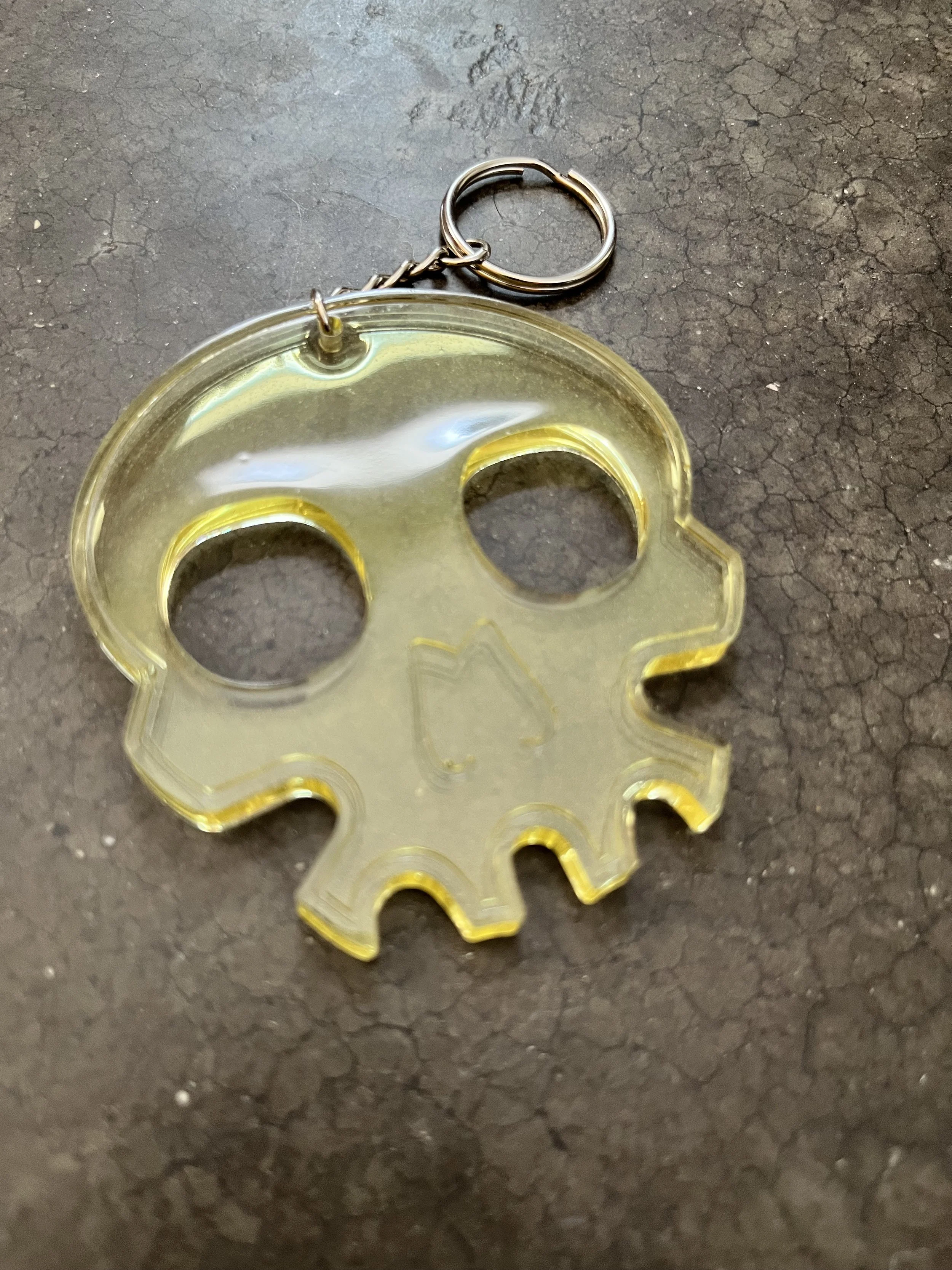 A handmade clear yellow resin epoxy emergency skull-shaped keychain.