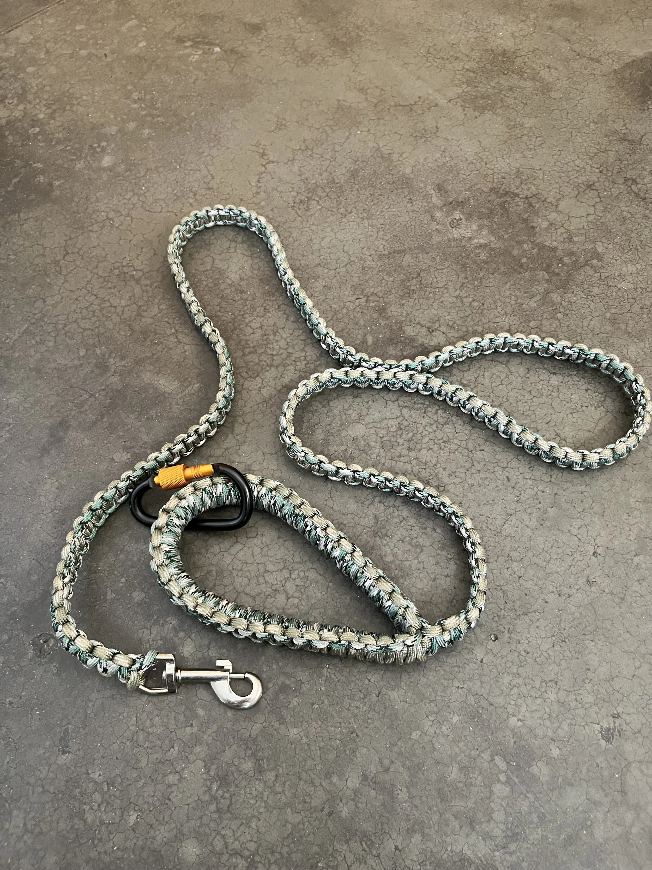 A handmade braided paracord dog leash with a carabiner and whistle.