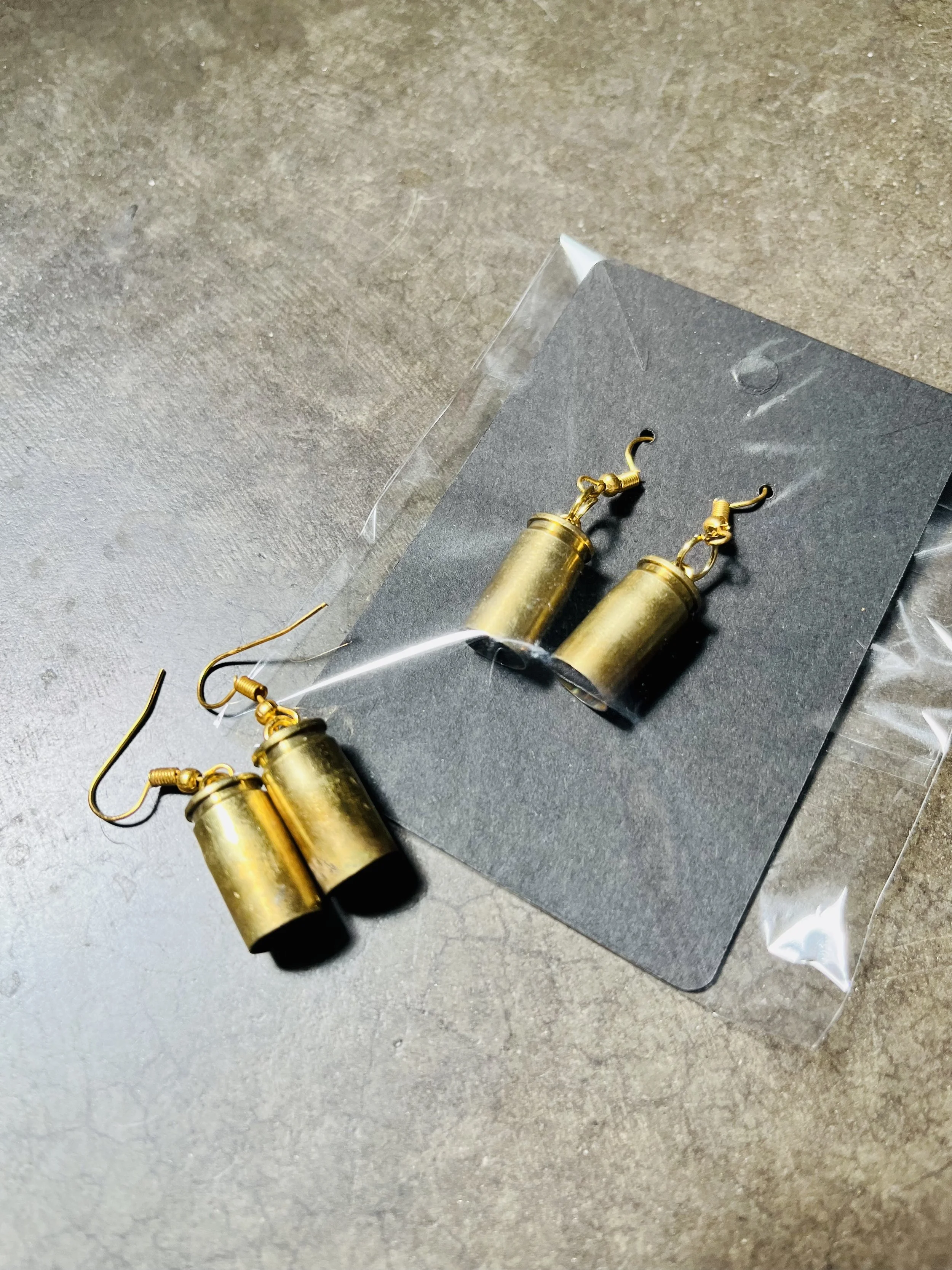 A pair of gun casing earrings .