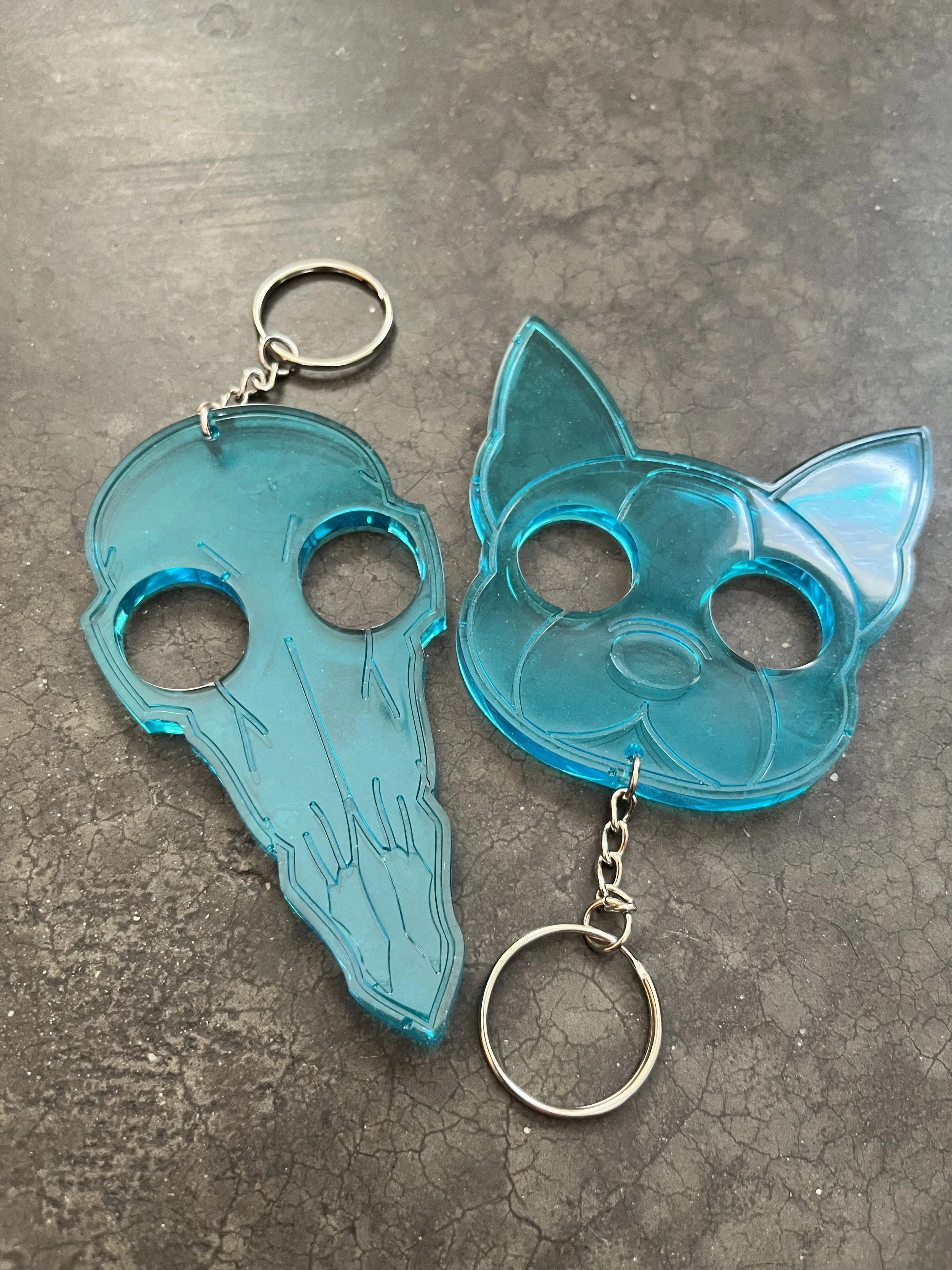 Blue handmade epoxy resin emergency keychains, on a textured surface.