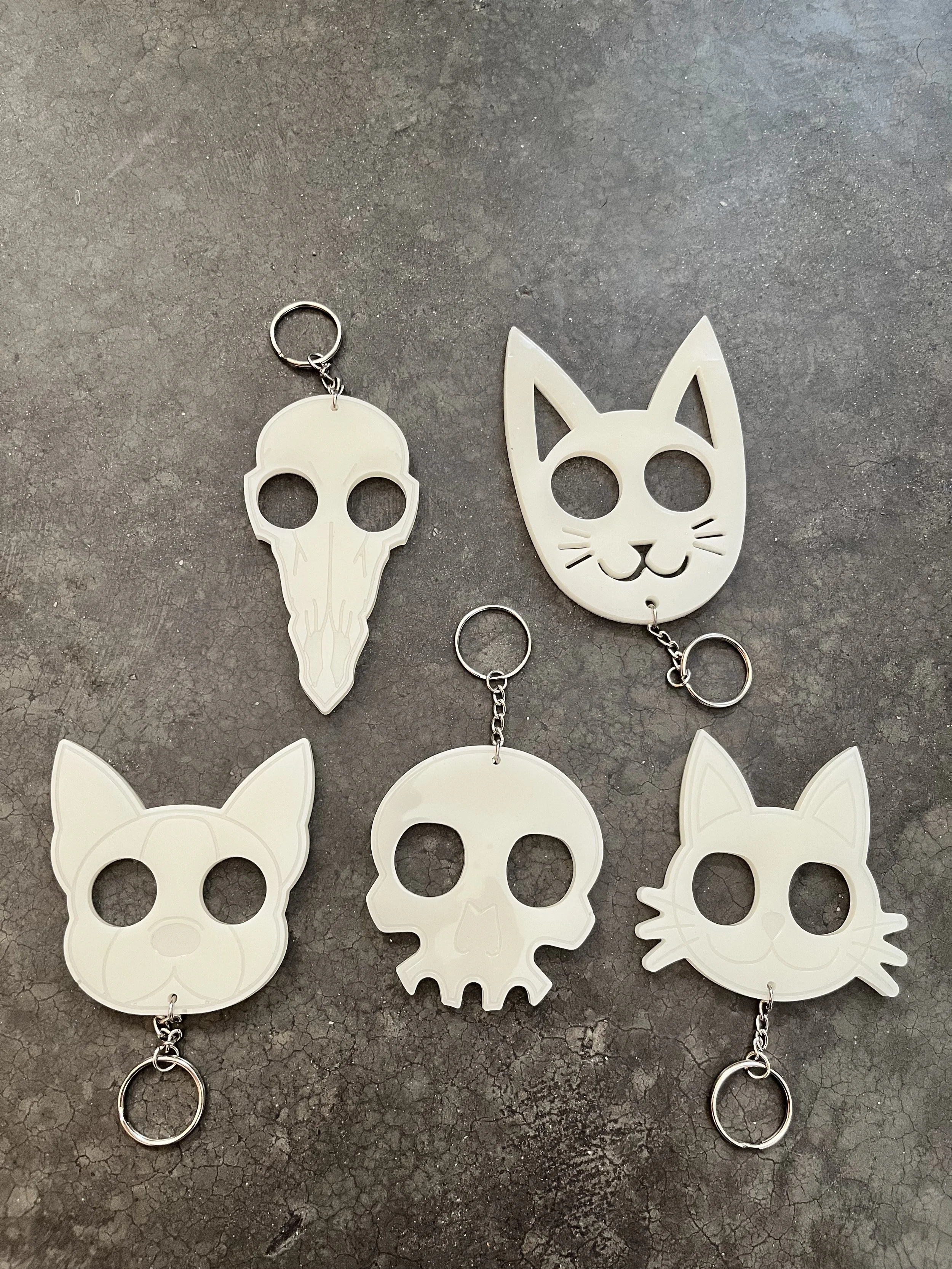 White handmade emergency epoxy resin keychains with multiple designs.