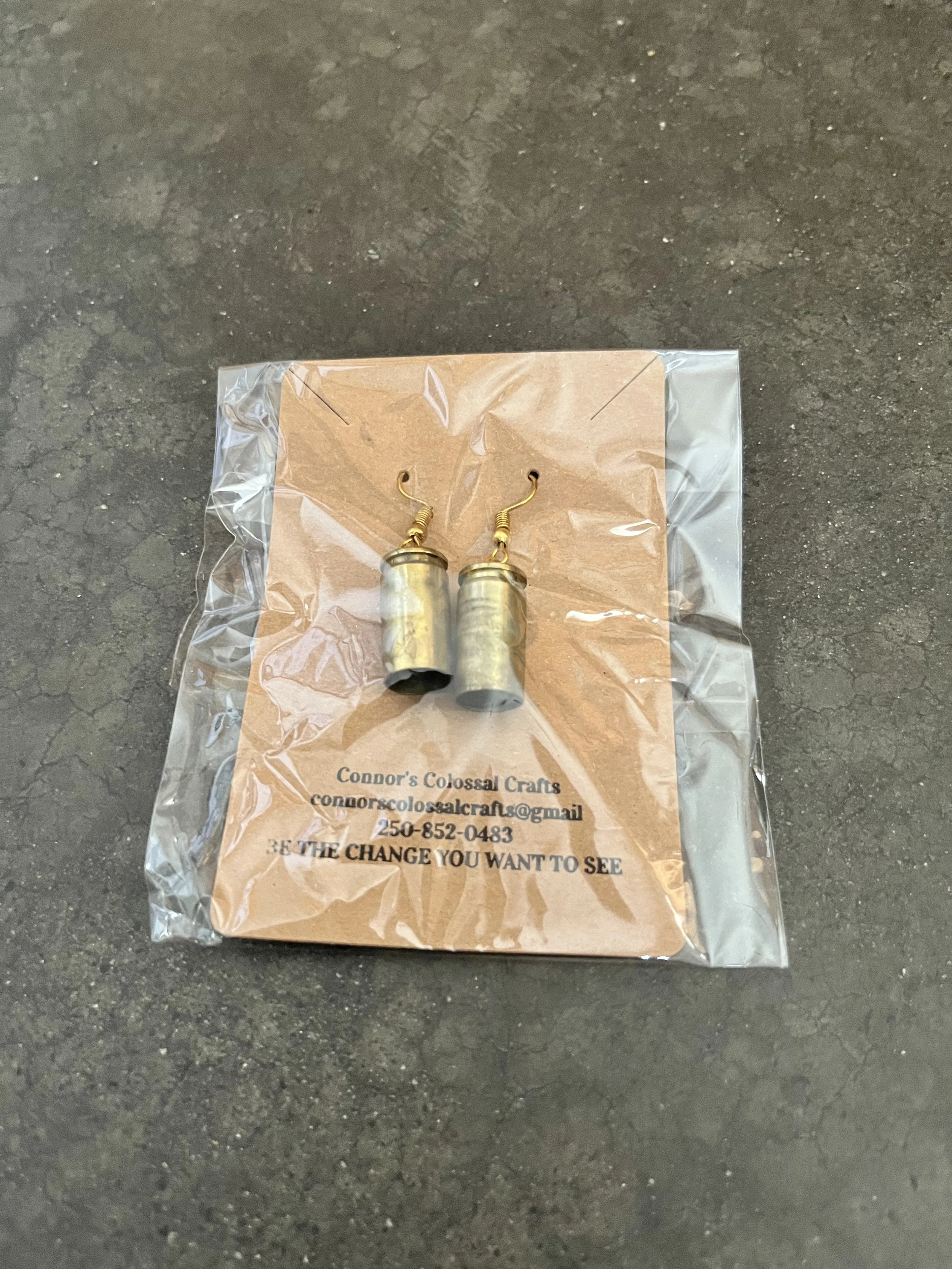handmade gun casing earrings wrapped in plastic.
