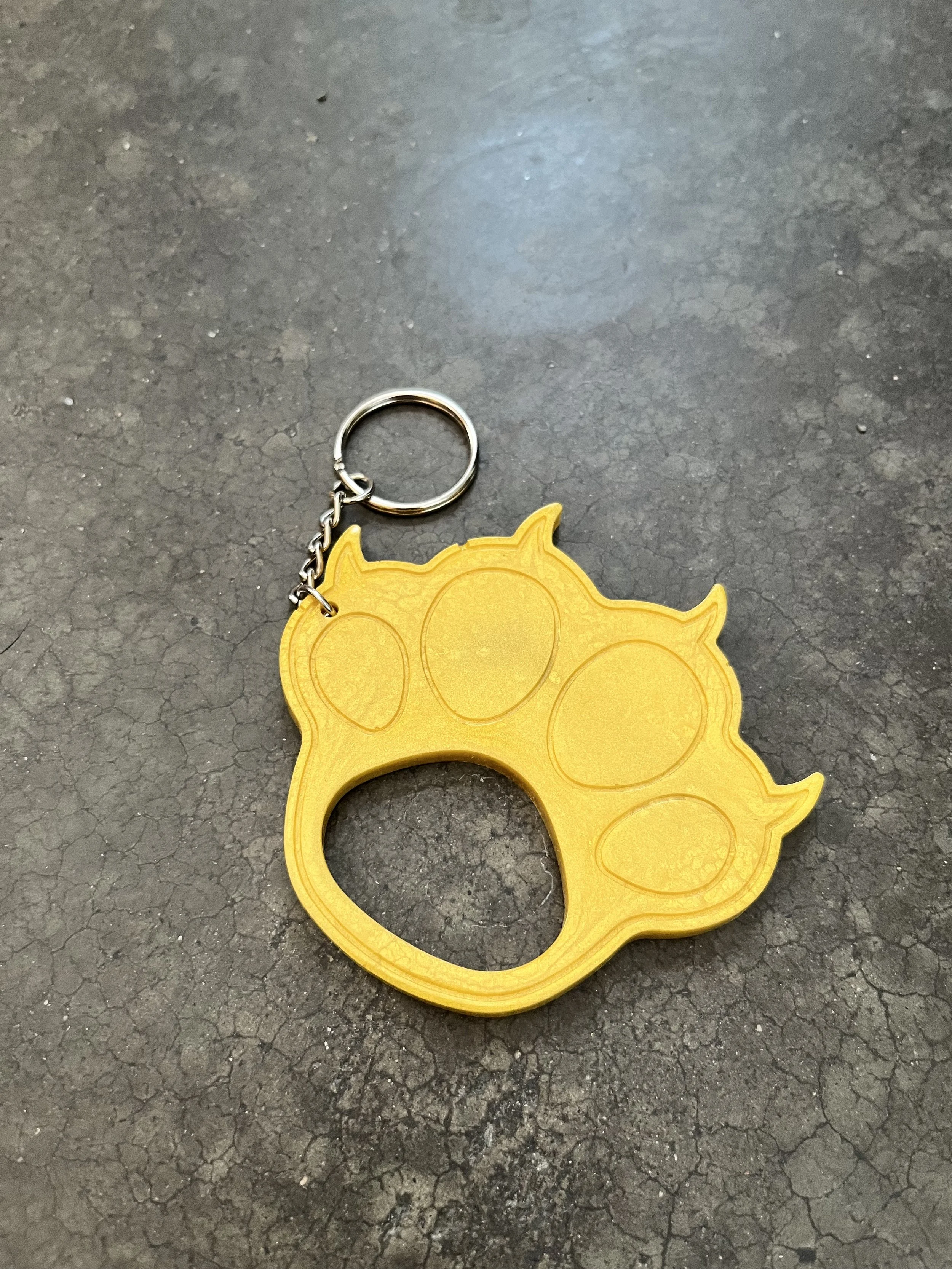 A handmade yellow paw-shaped resin epoxy emergency keychain.