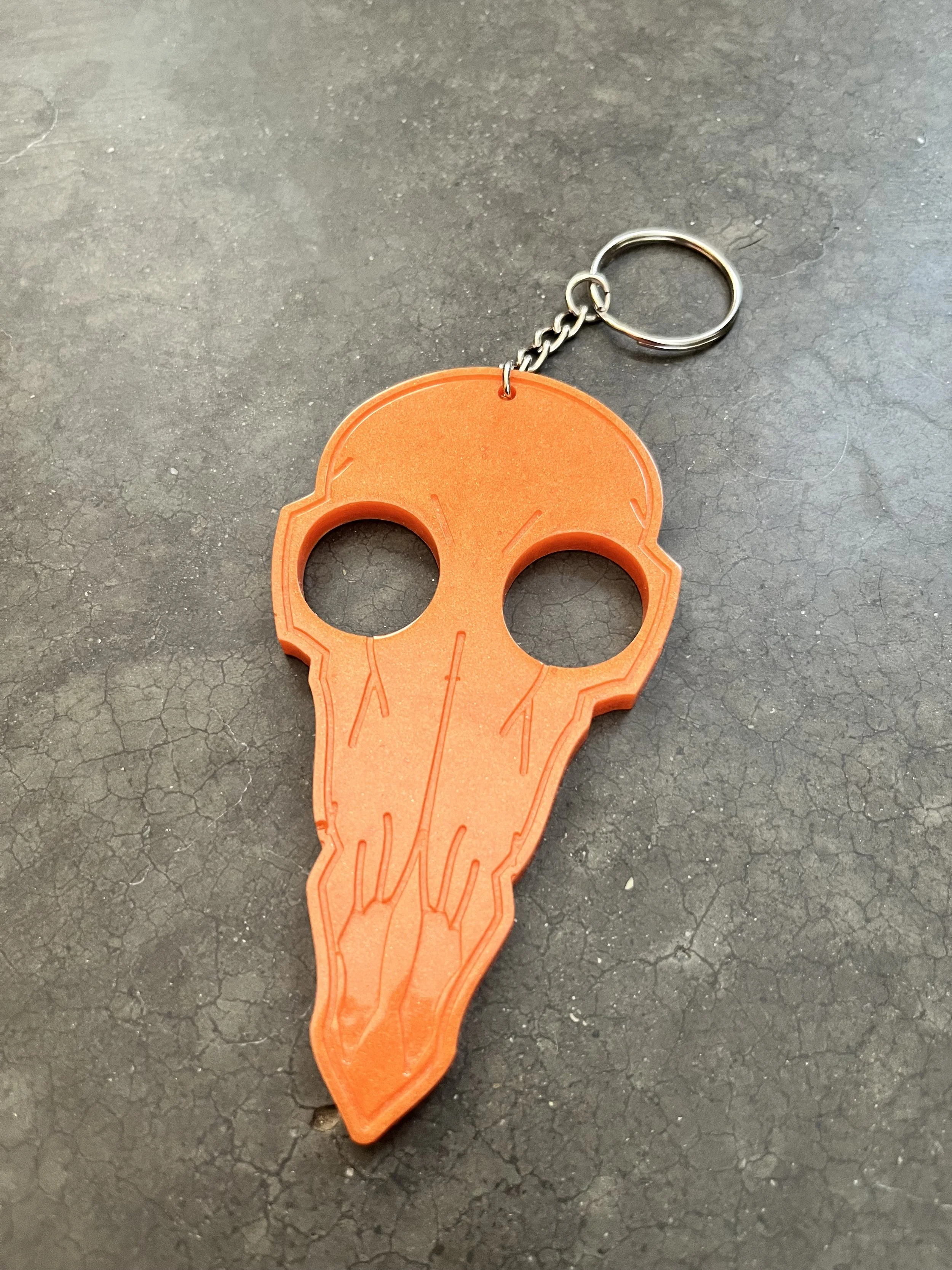Orange handmade epoxy resin emergency keychain in the shape of a skull.