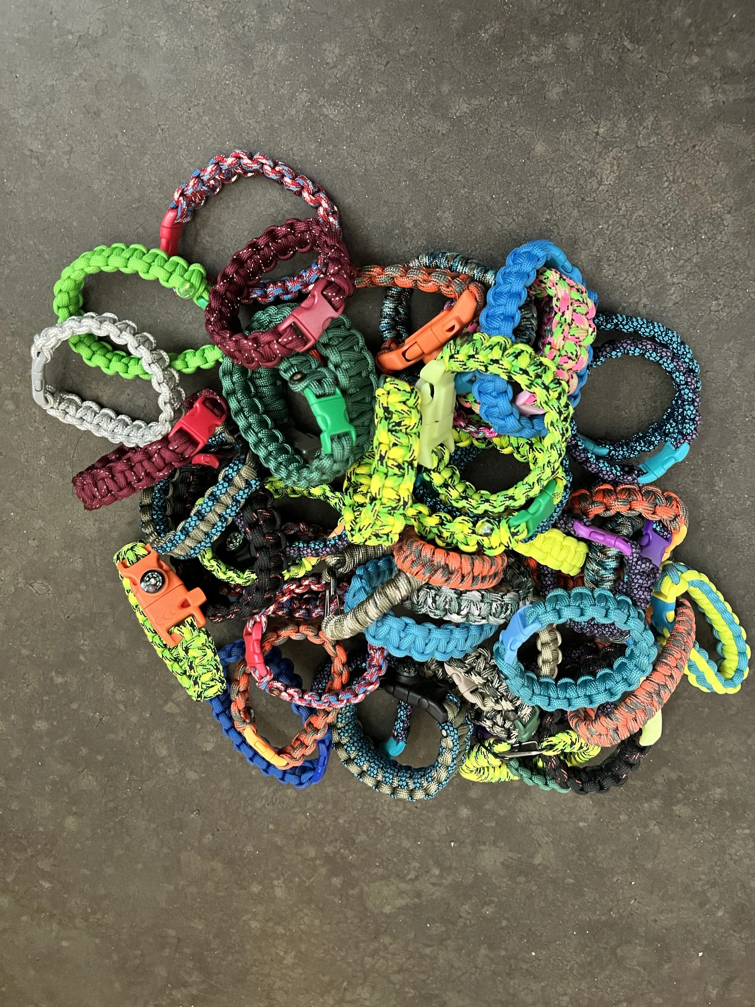 An assortment of handmade colorful, braided paracord bracelets.