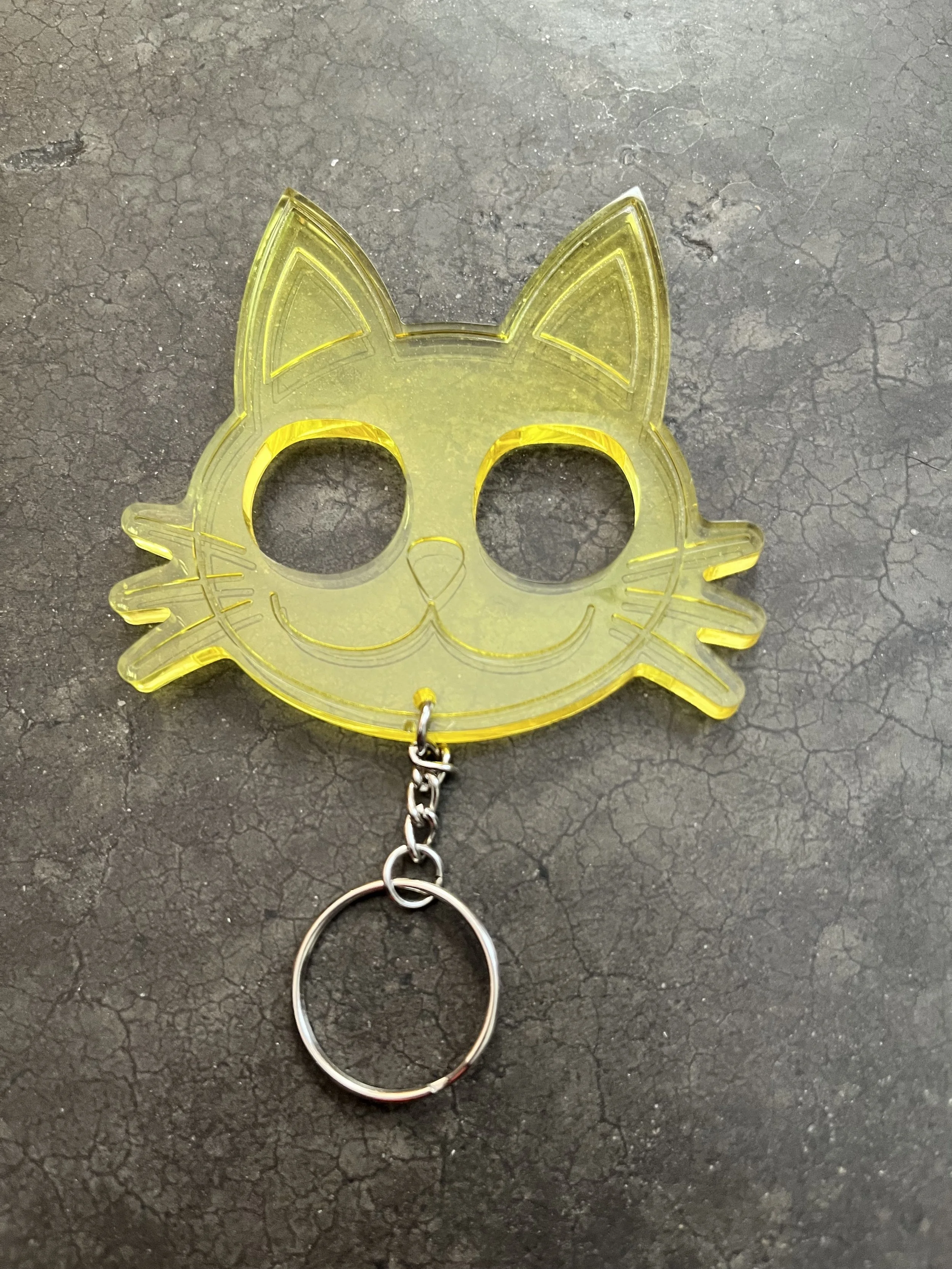 A yellow resin epoxy emergency keychain, on a textured black surface.