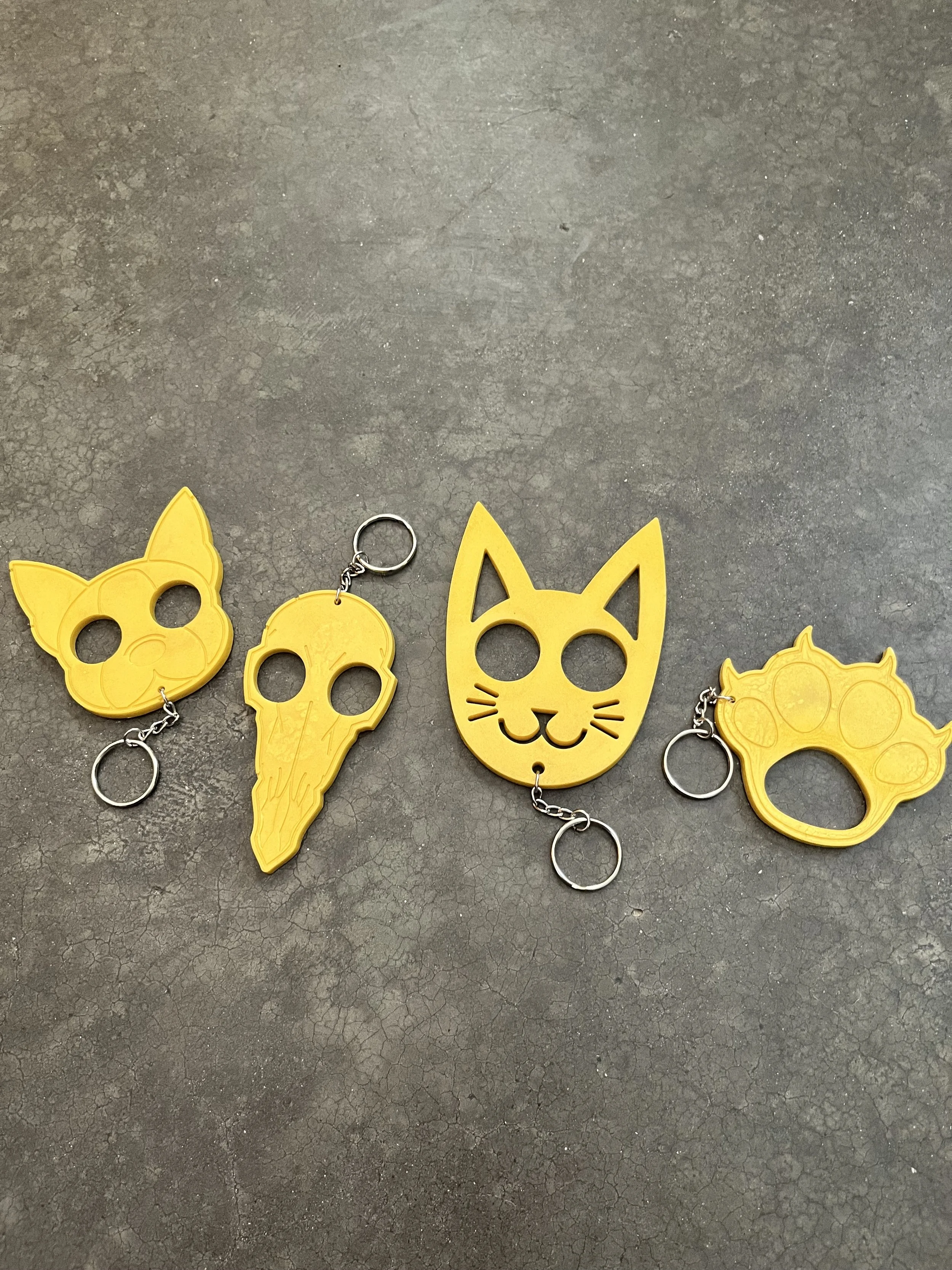 Yellow cat-themed keychains  on a cracked concrete surface.