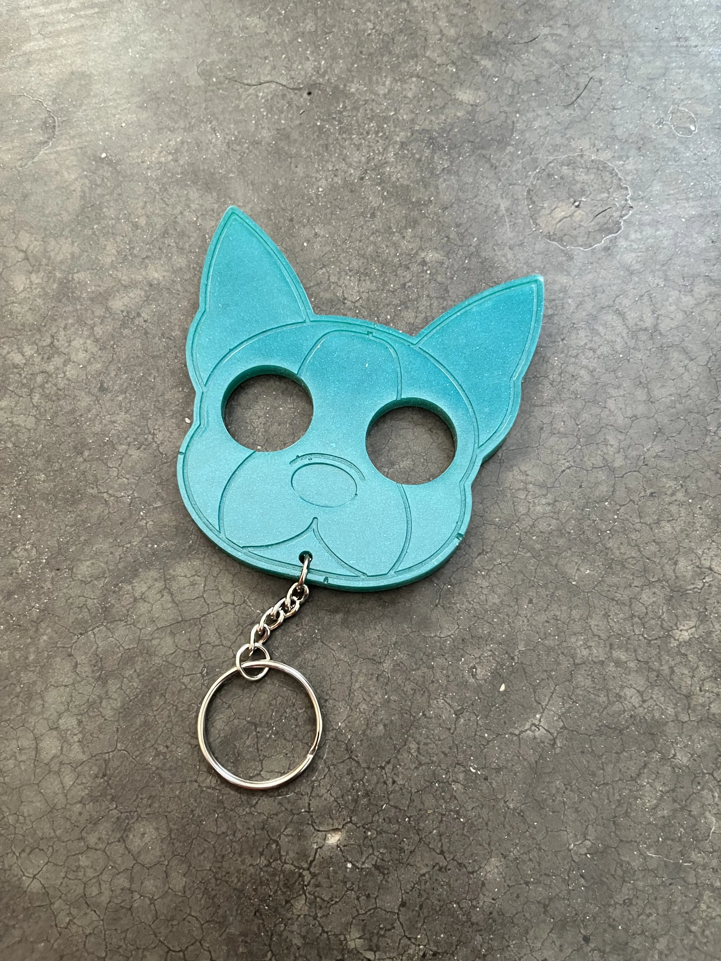 A blue keychain in the shape of a dog's head made out of epoxy resin.