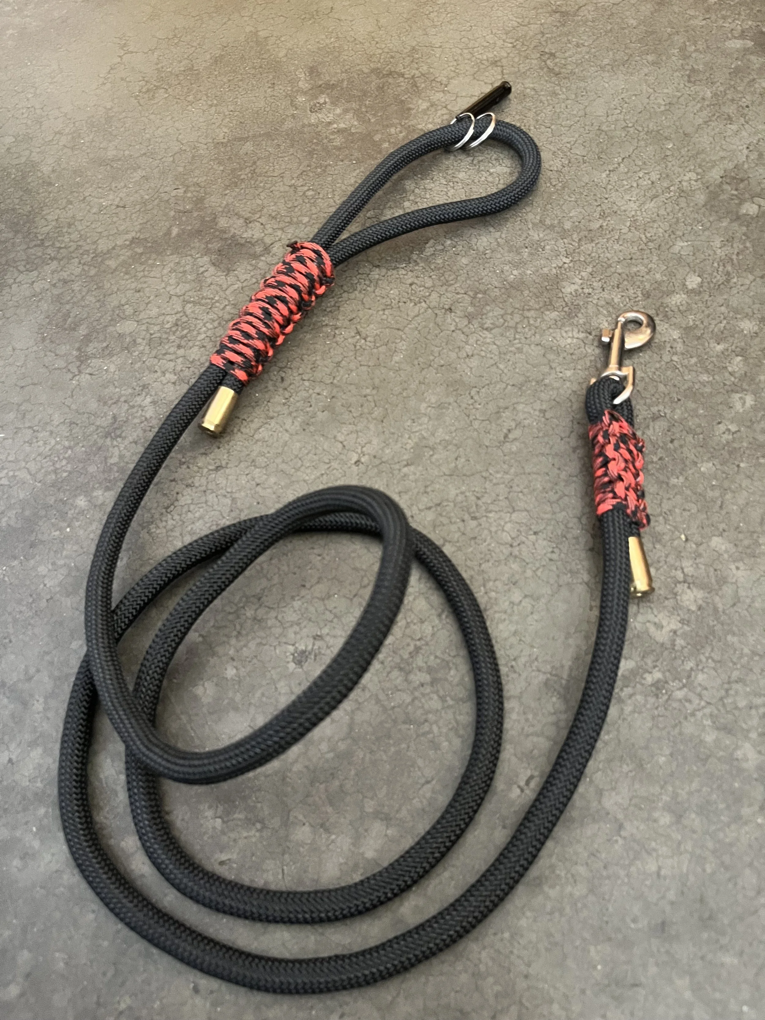 A handmade black and orange dog leash with gun casings.Made with paracord.