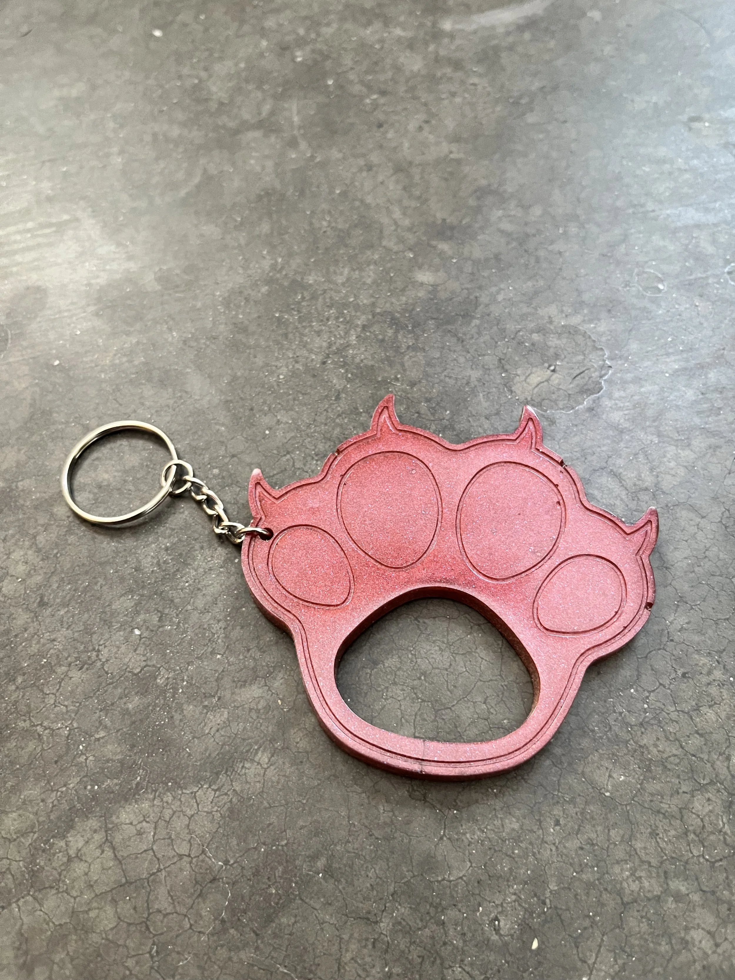 A handmade resin epoxy emergency keychain in the shape of a paw.