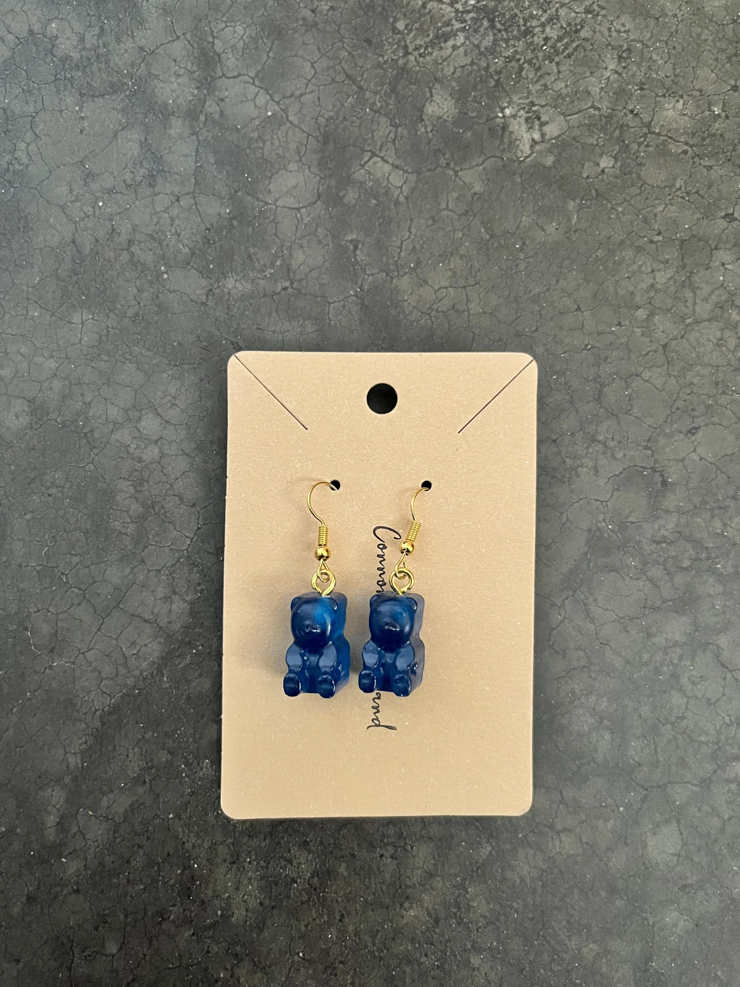 Pair of blue gummy bear earrings displayed on a beige card.