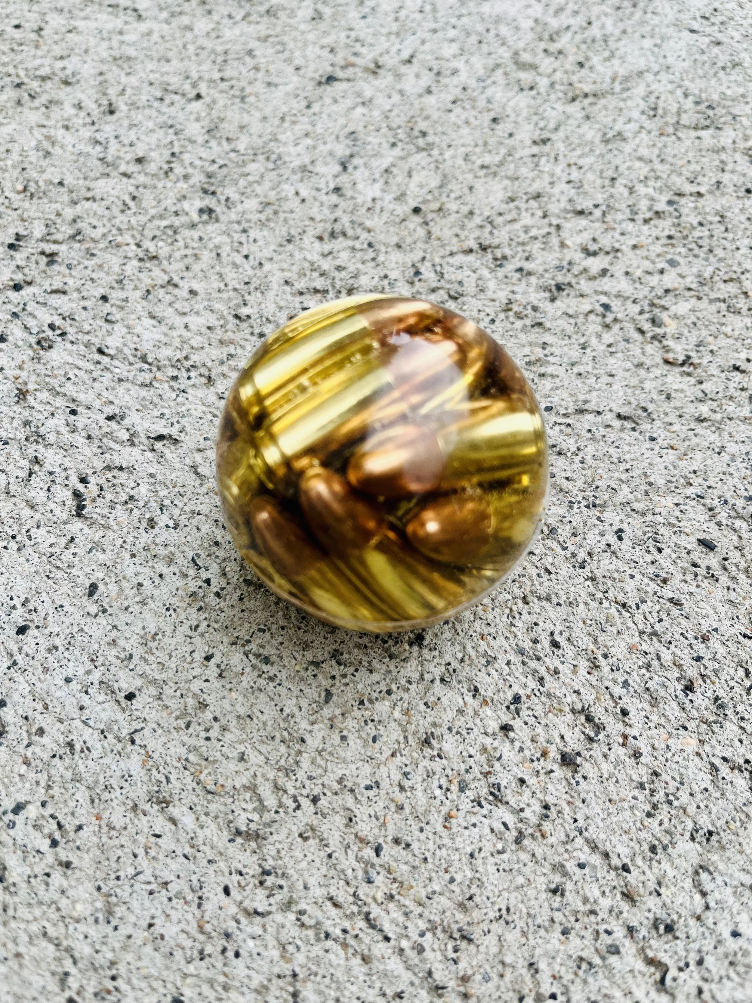 A shiny golden resin epoxy ball made from 9mm bullets.