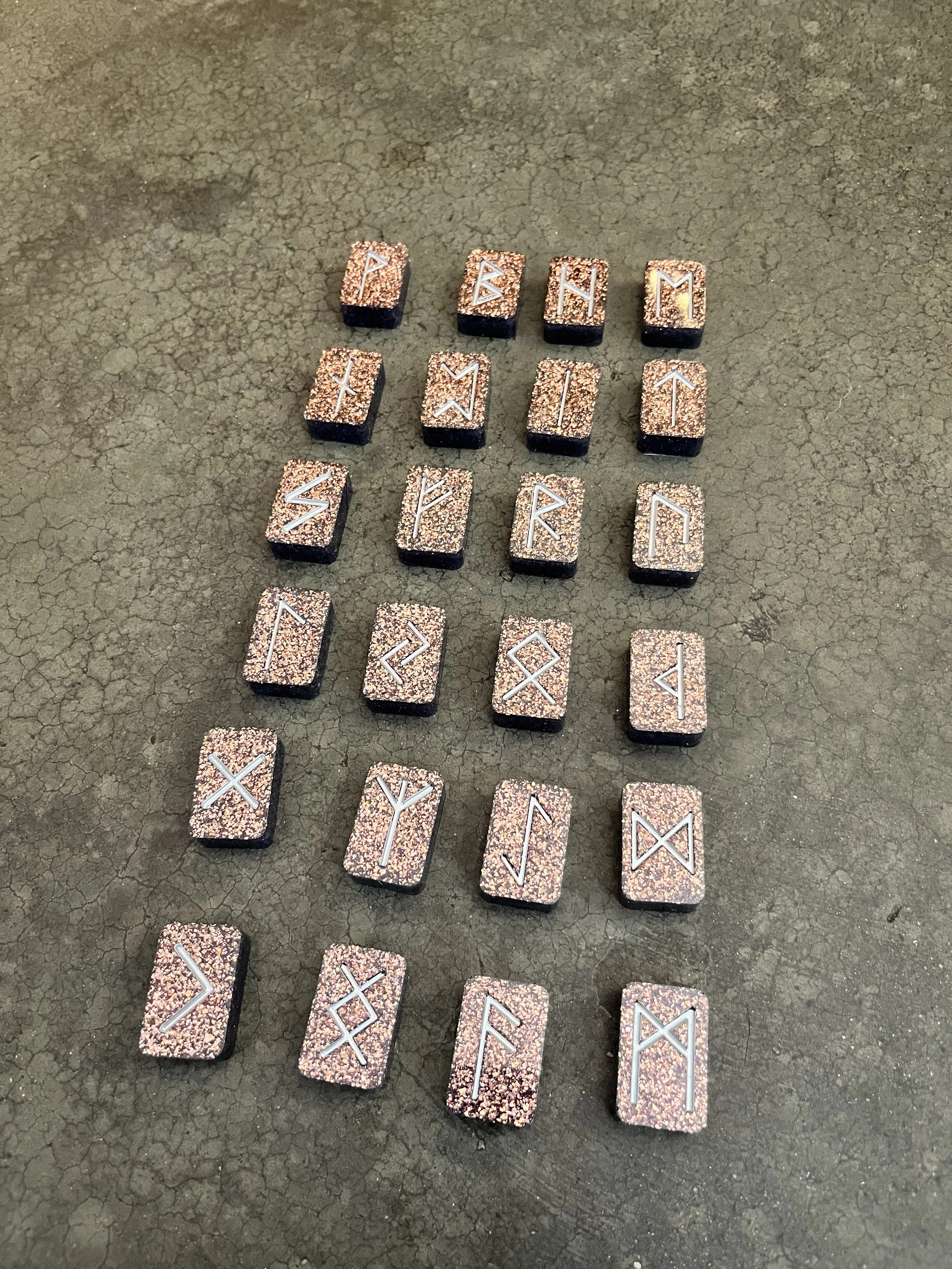 A collection of runic tiles arranged on a cracked, gray surface.