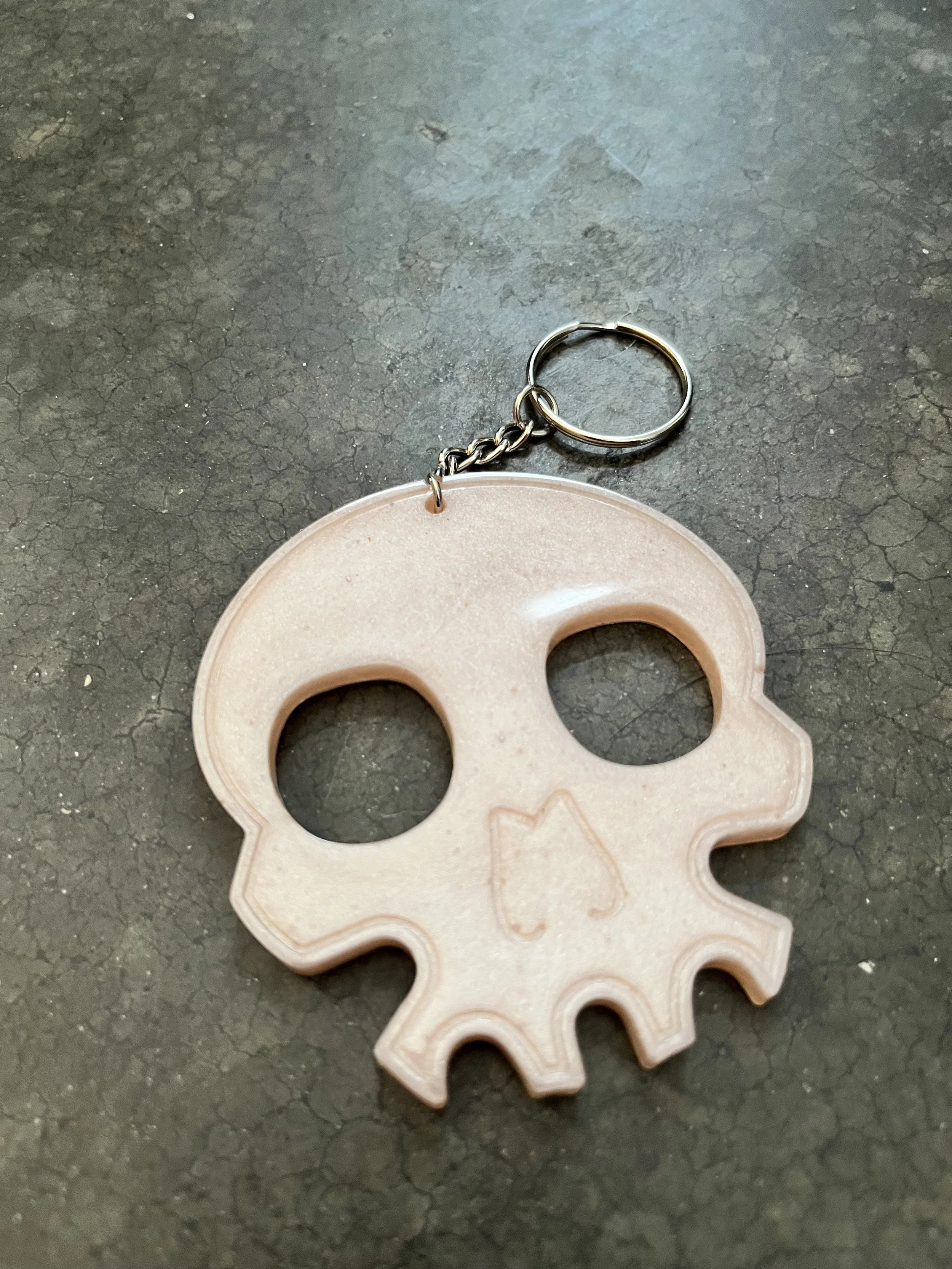A handmade resin epoxy emergency keychain with a skull-shaped design.