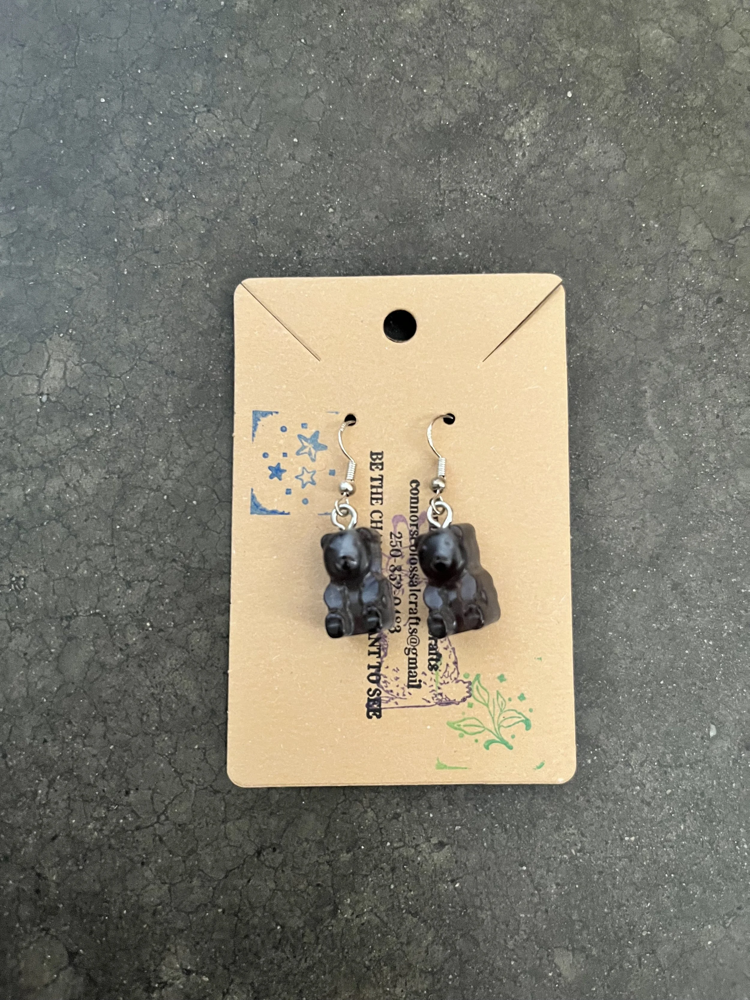 A handmade pair of black resin epoxy gummy bear earrings.