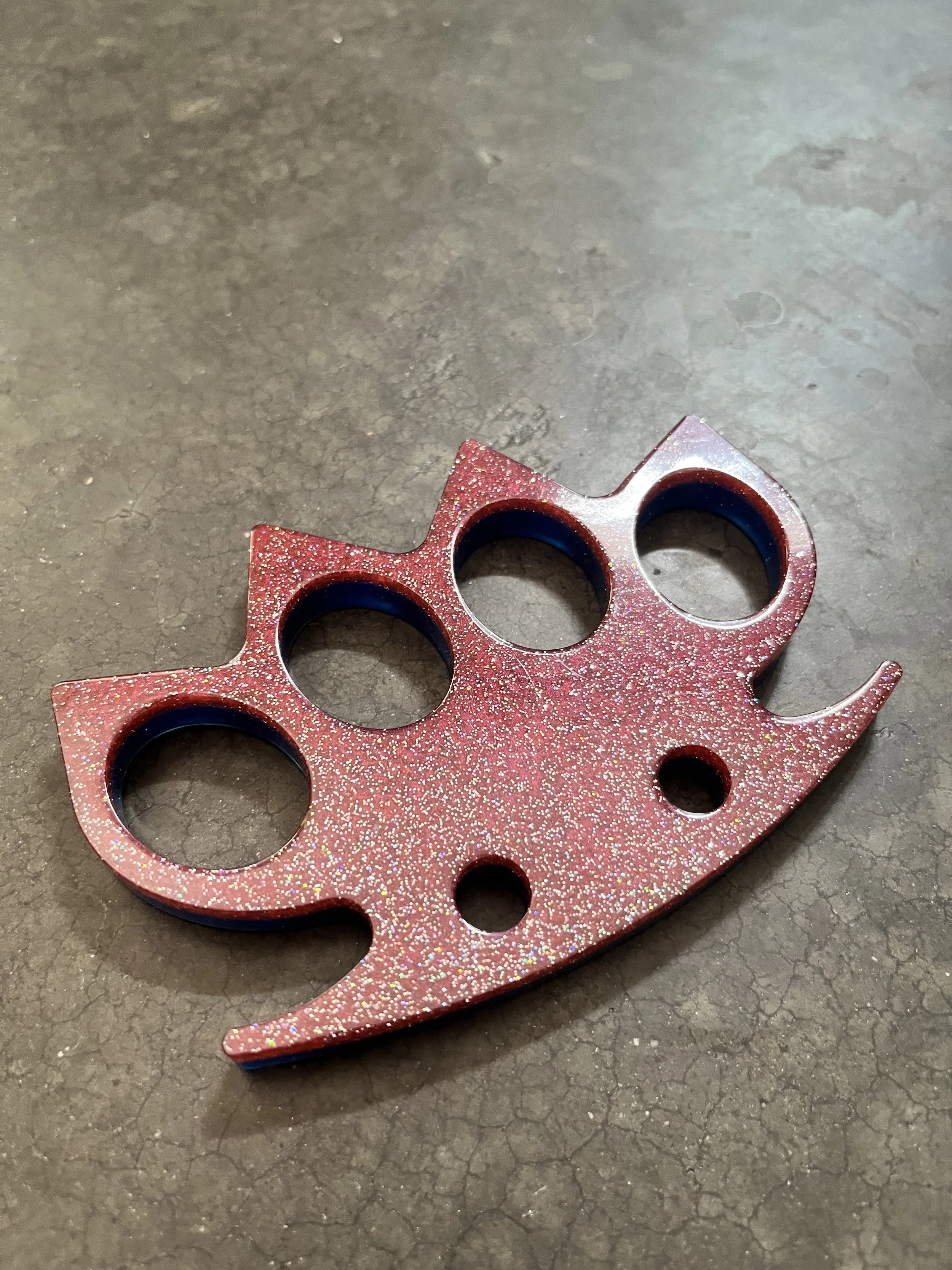 A red glittery knuckle keychain made from epoxy resin.