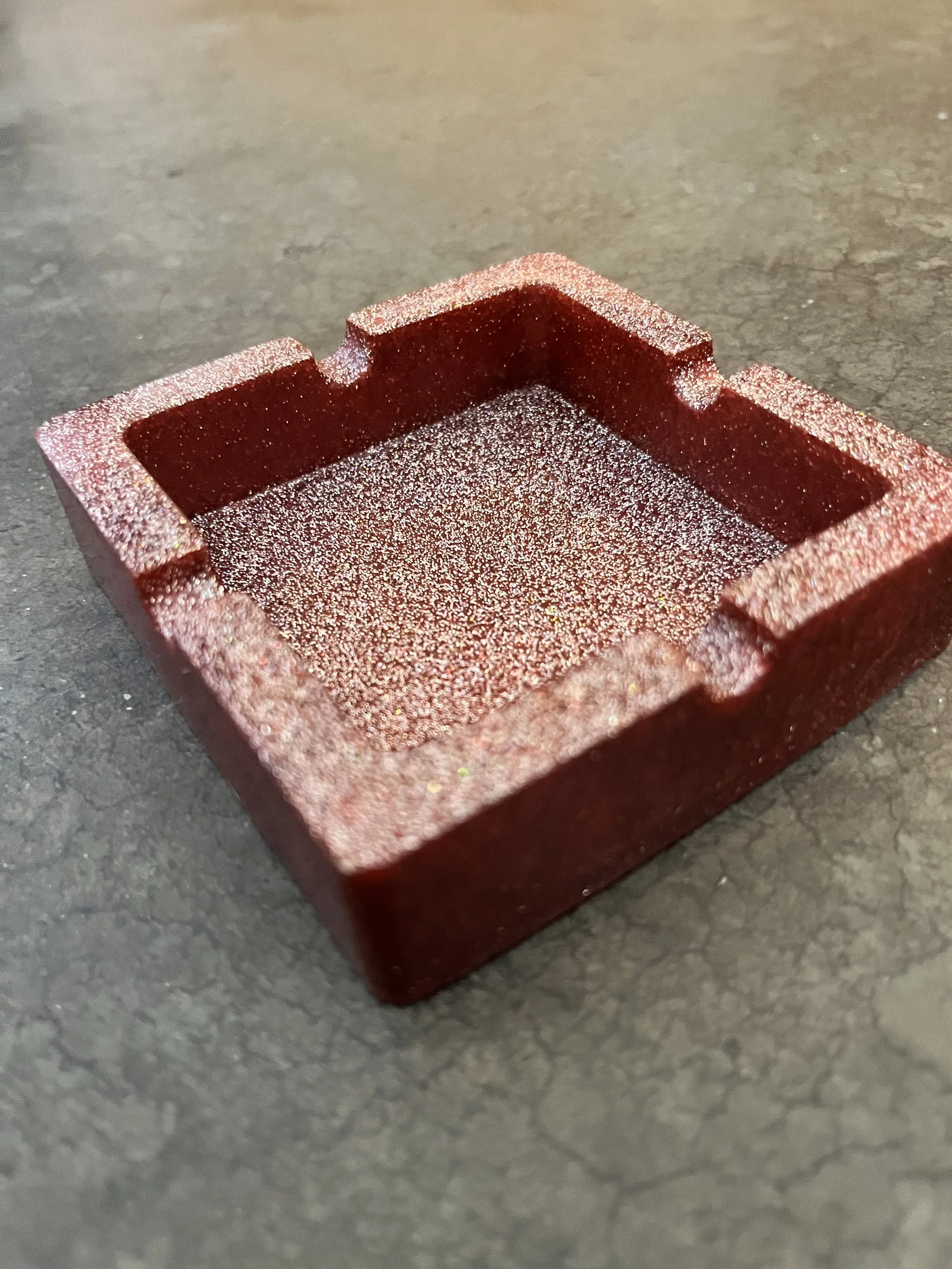 Close-up of a handmade red, textured, rectangular ashtray/bowl.