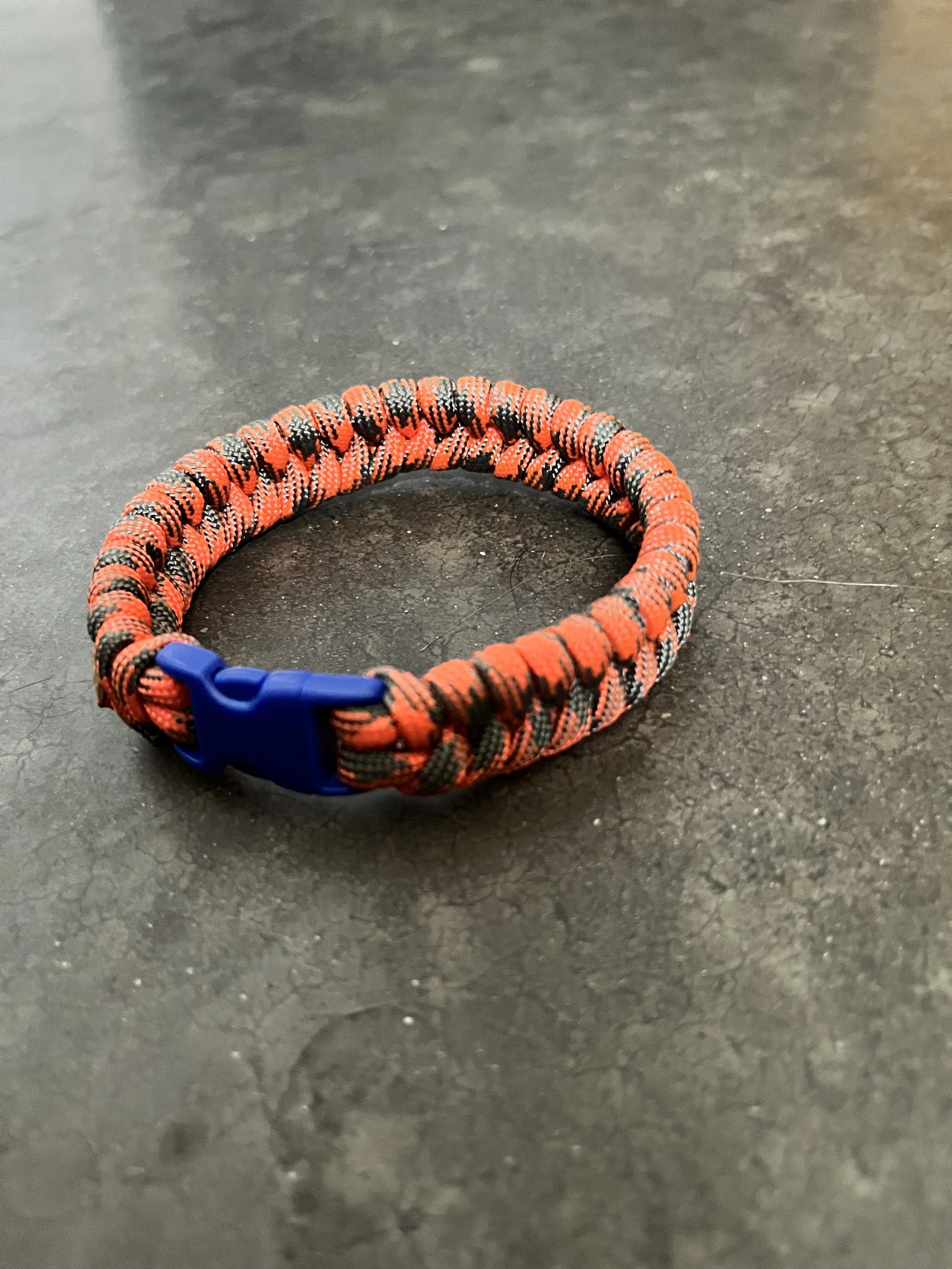 A handmade orange and blue braided paracord bracelet.