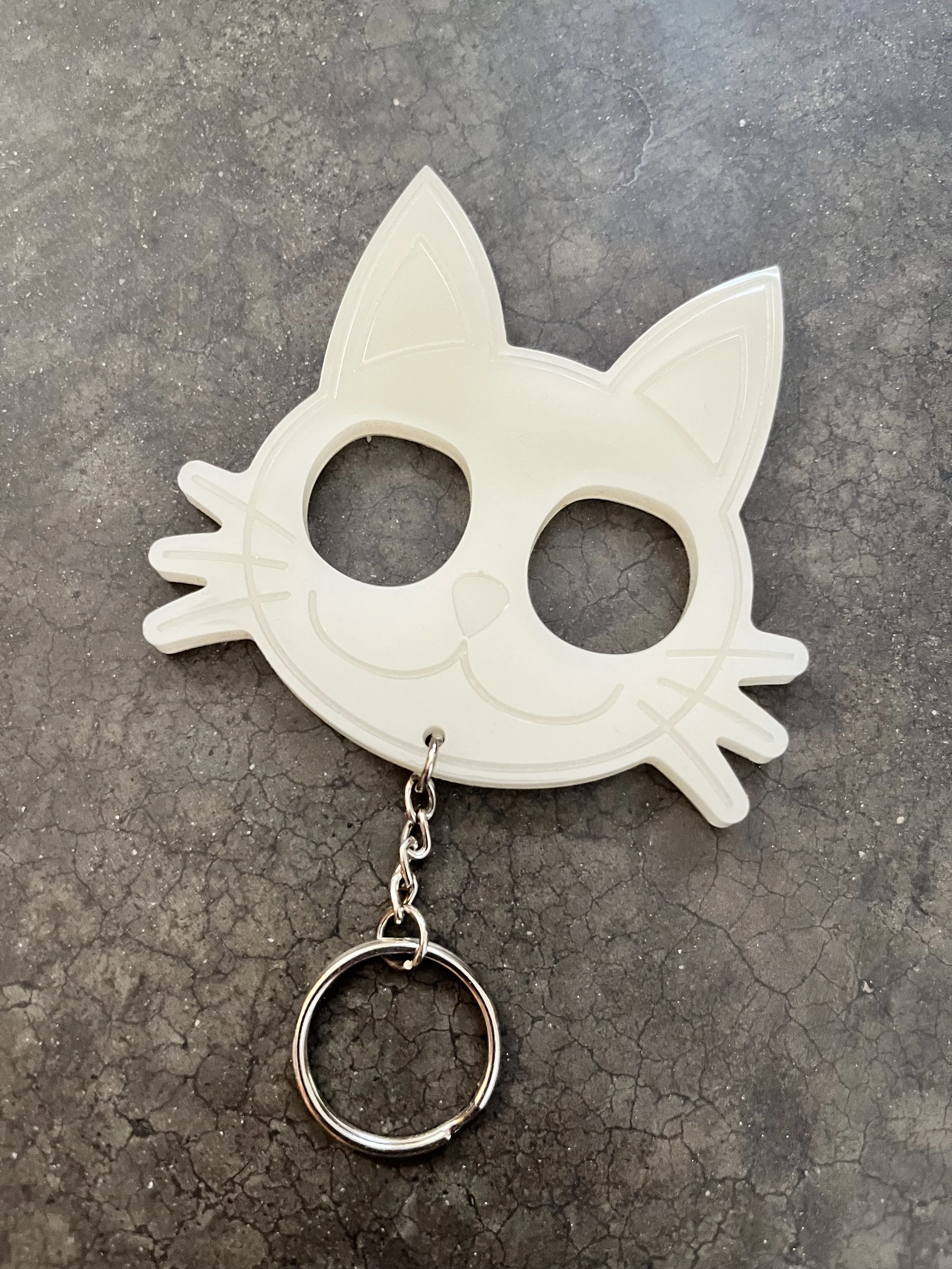 A handmade white, cat-shaped resin epoxy emergency keychain.