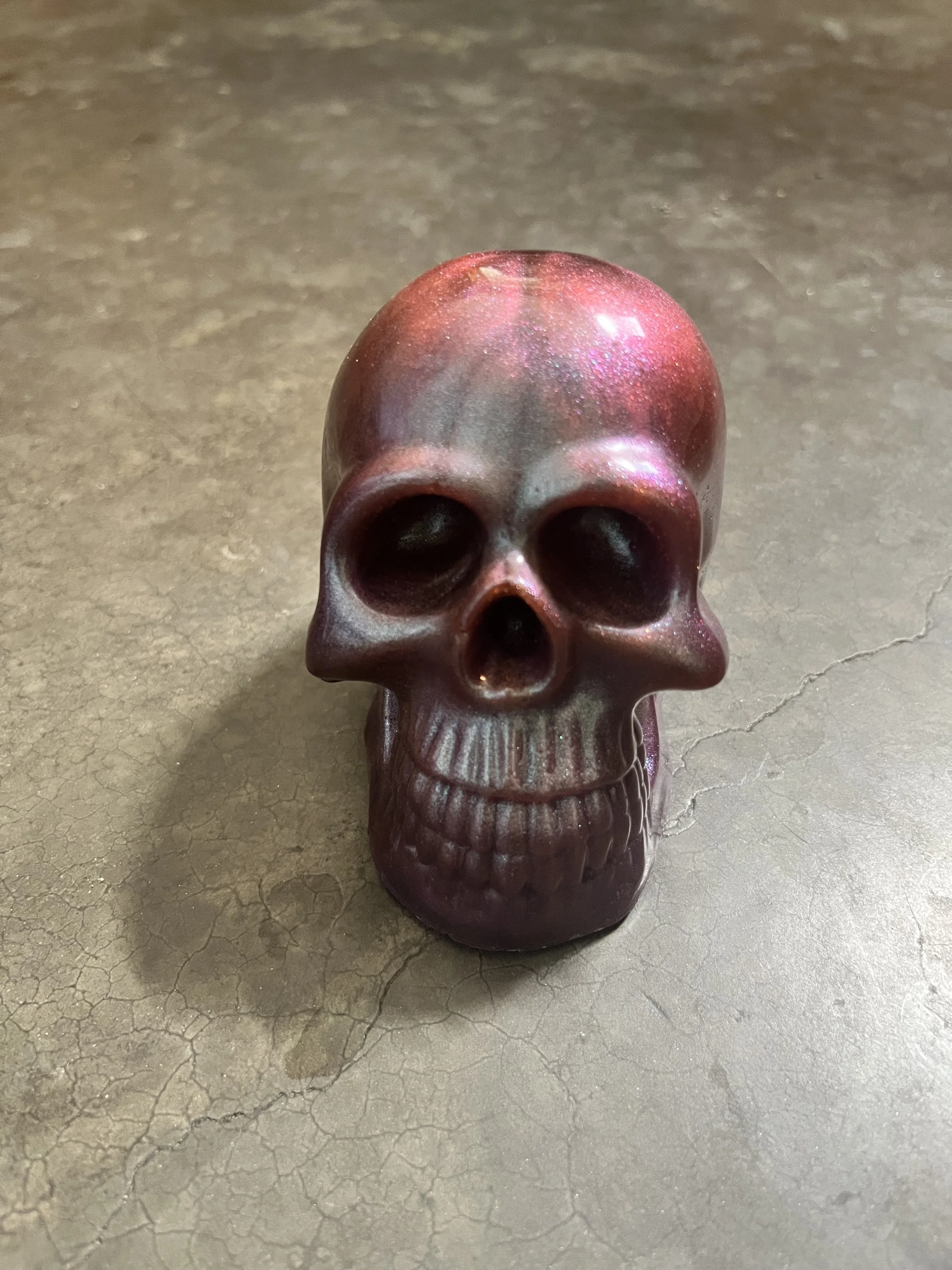A handmade epoxy resin skull on a concrete floor.