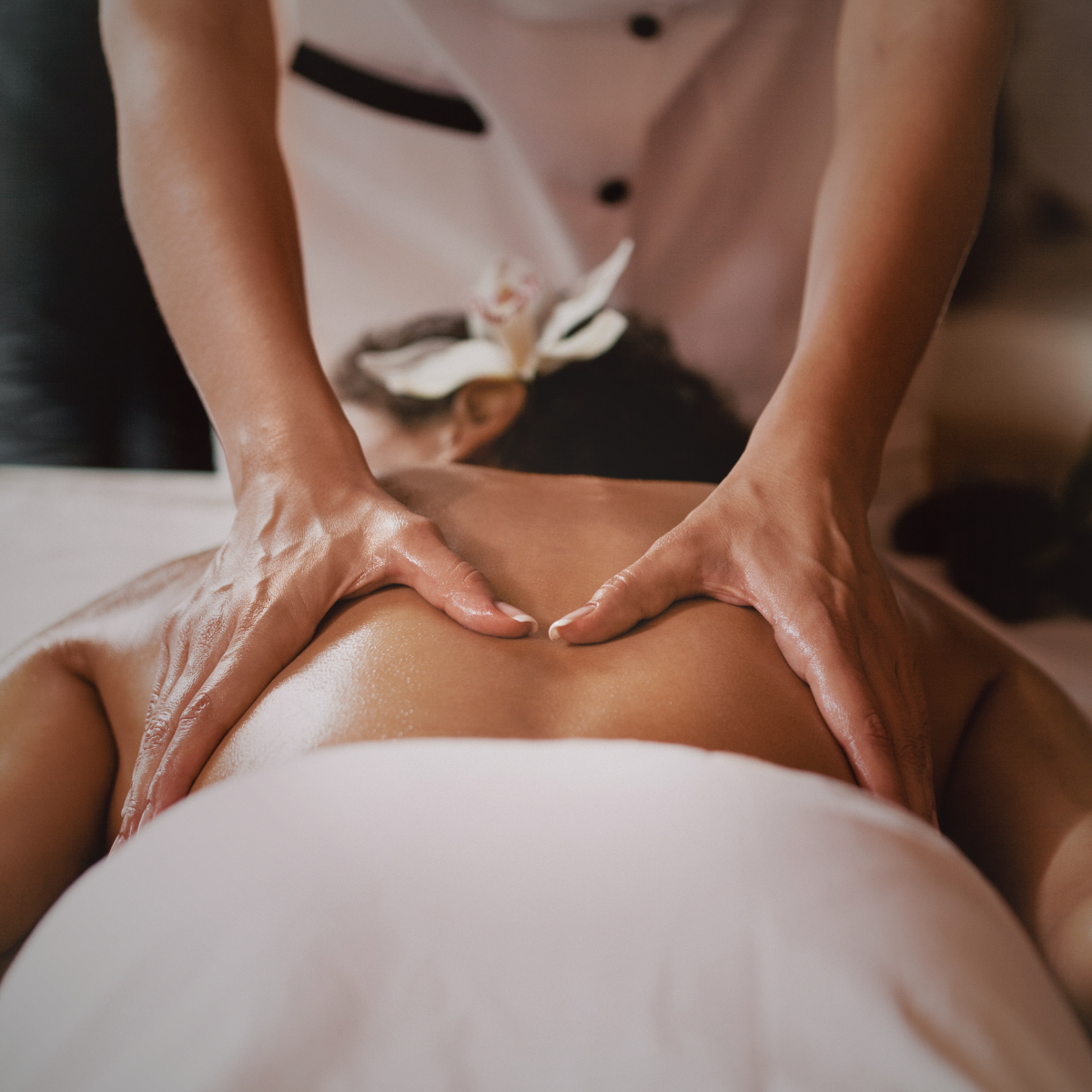 A person receiving a massage on their back from a therapist in a spa setting.