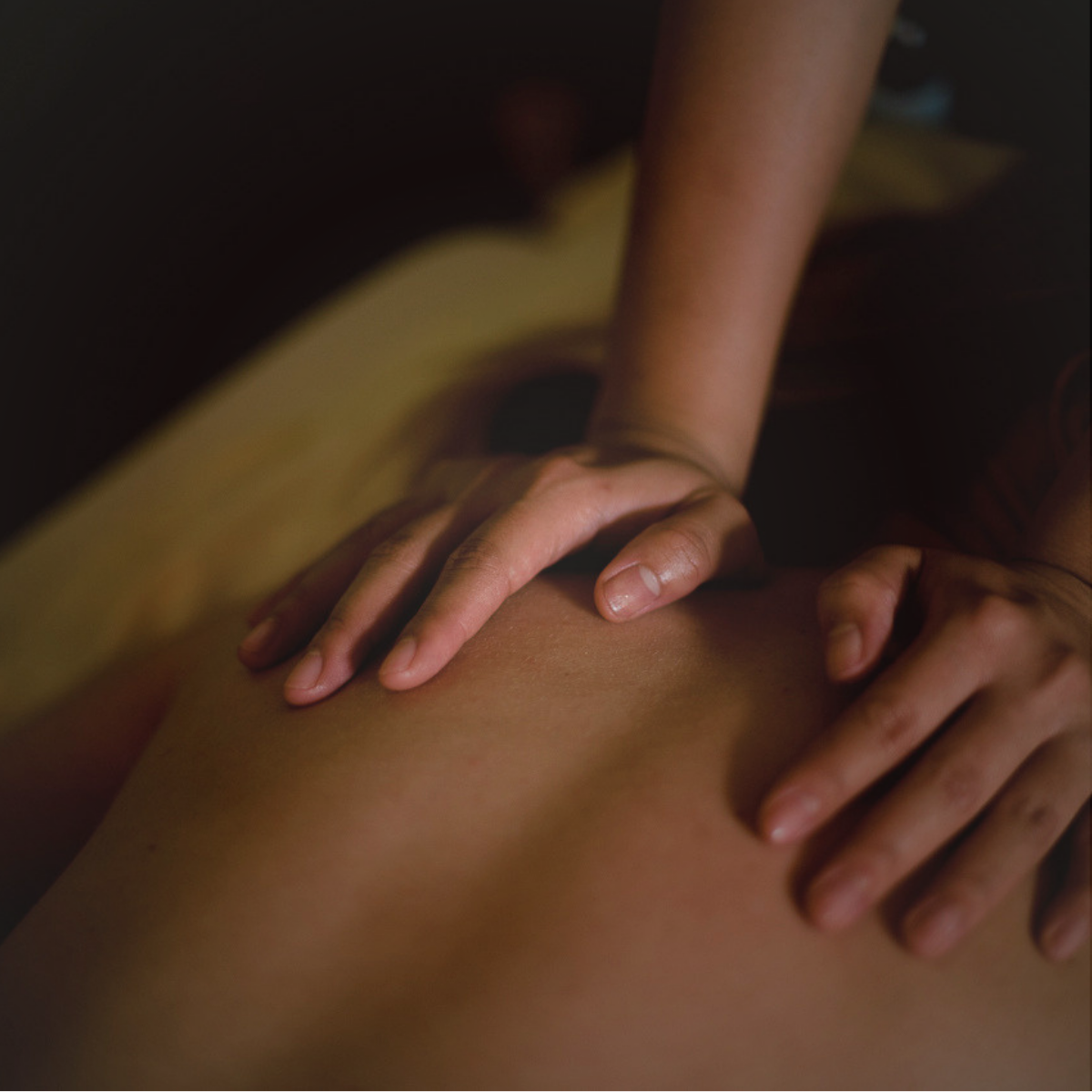 Close-up of hands giving a massage on a person's back.