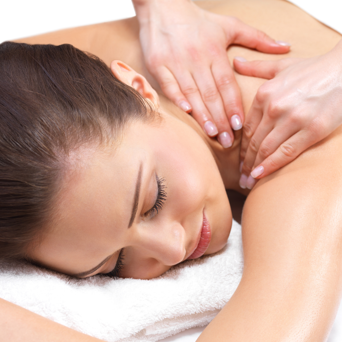 Woman receiving a shoulder massage while lying on a white towel