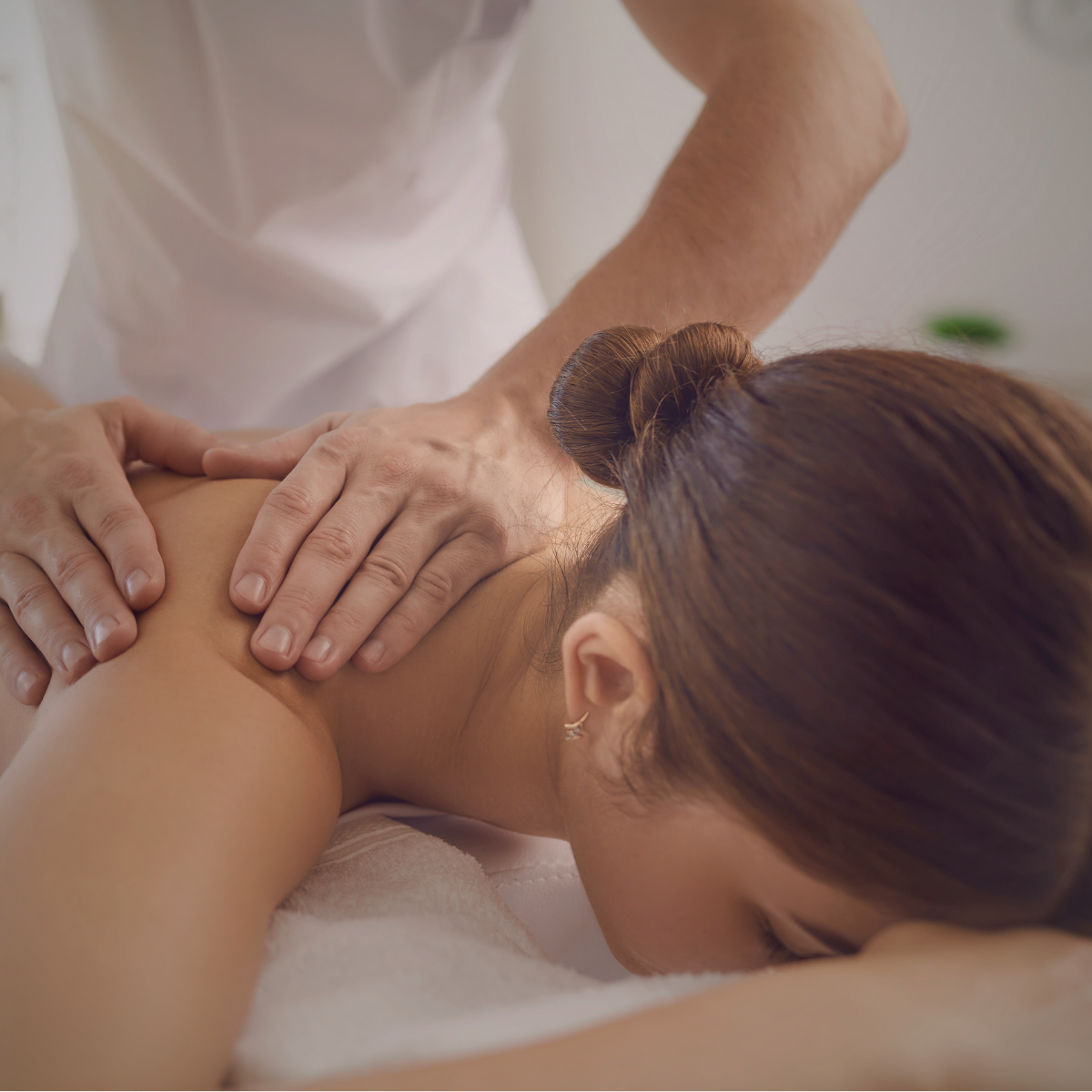 A woman receiving a back massage from a massage therapist in a spa or wellness setting.
