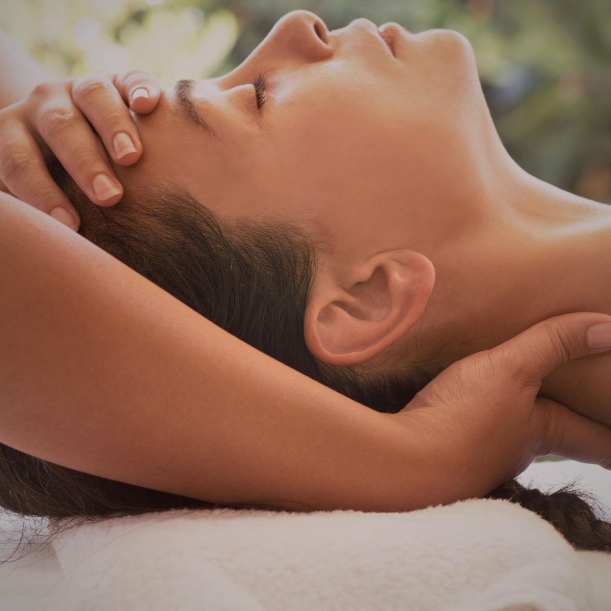 Woman receiving a massage, lying on her back with eyes closed.