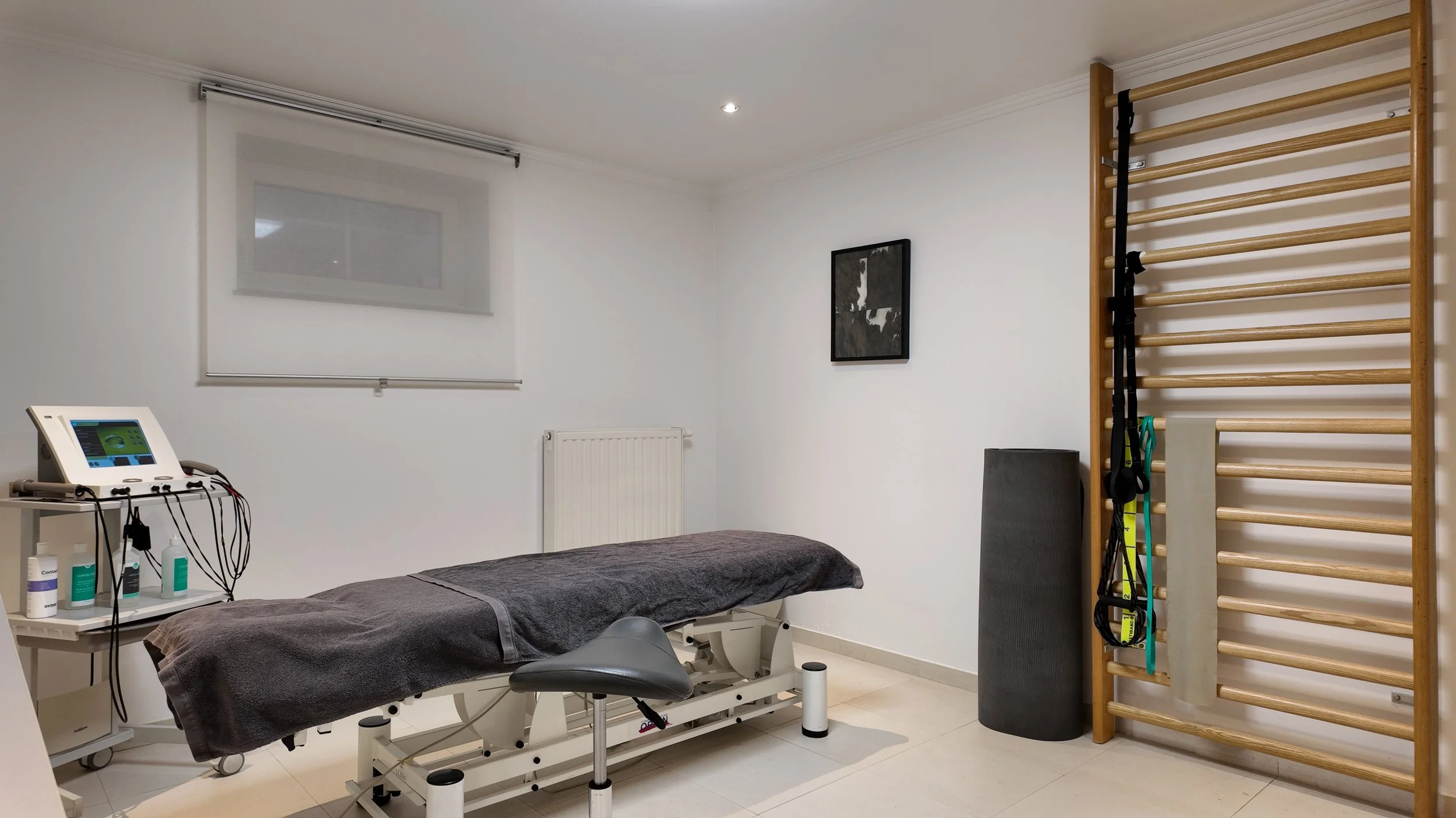 Salle de physiothérapie avec un lit, un équipement médical, un mur d'exercices avec barres horizontales et des accessoires de sport suspendus