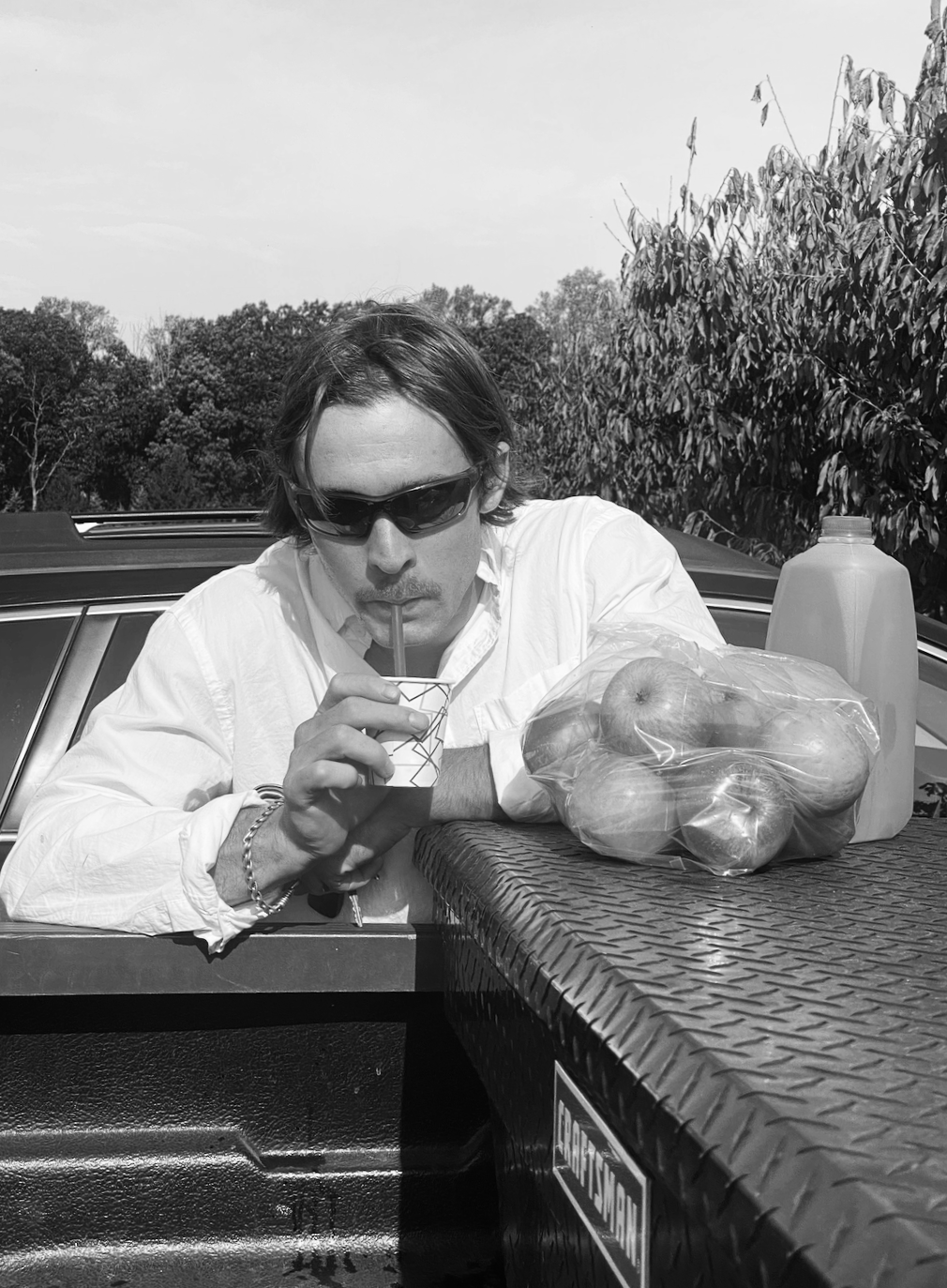 Drift House chef beside fresh produce and a house beverage during food sourcing.