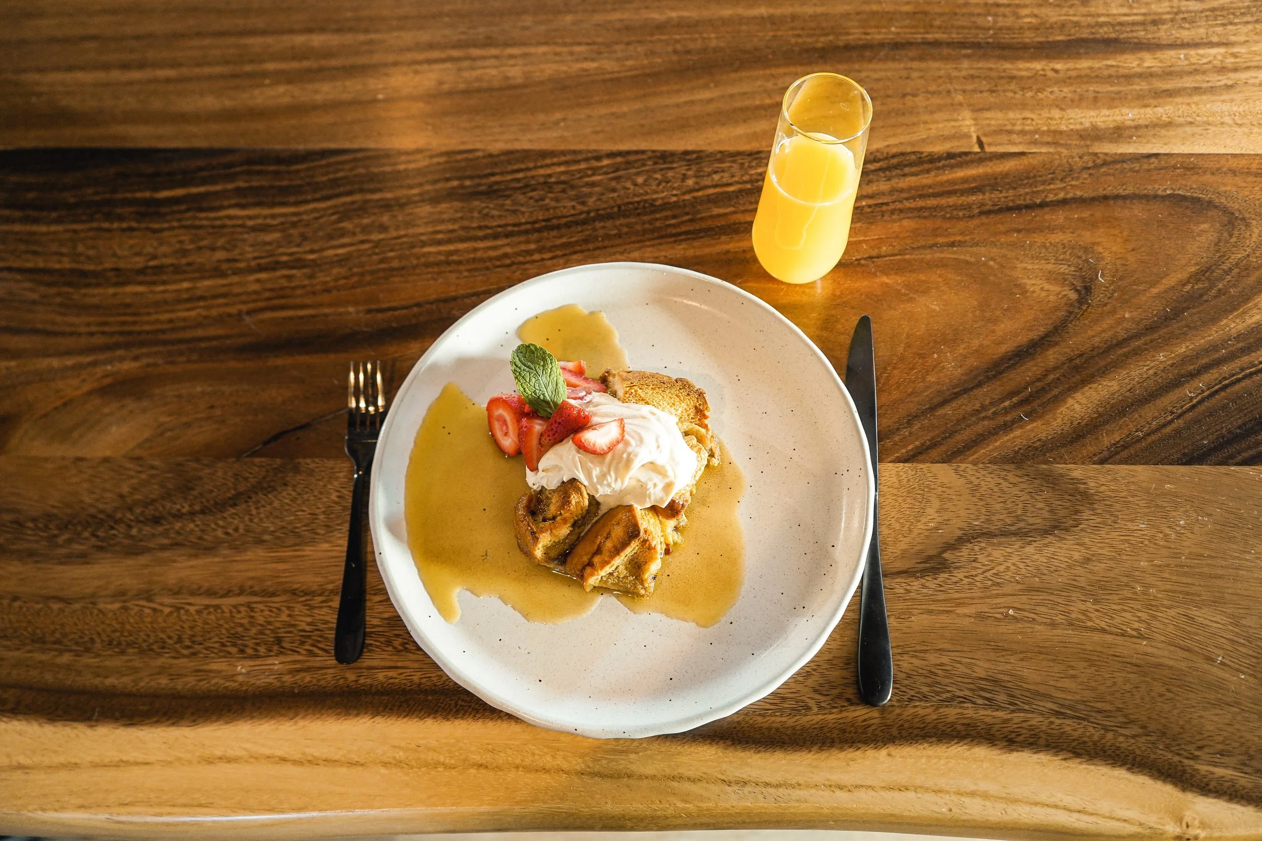 French toast bake with strawberries, maple crème fraîche and orange juice for breakfast.