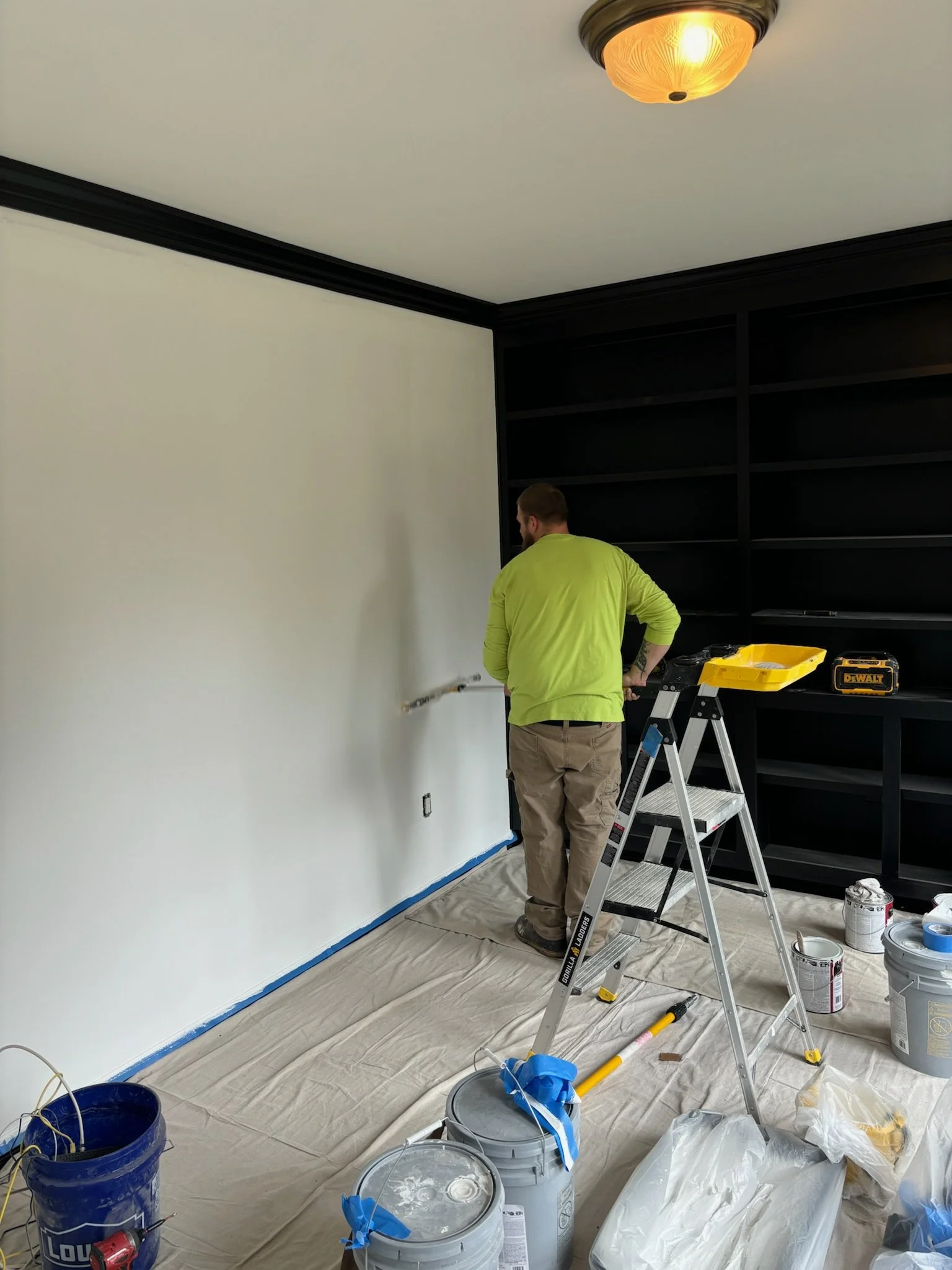 a man paints an interior wall with a paint roller