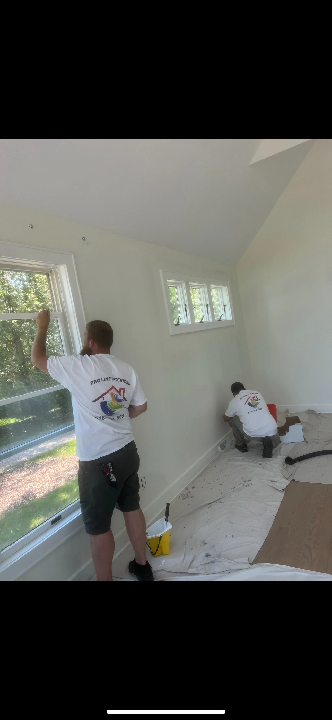 two men paint an interior room of a home in white paint