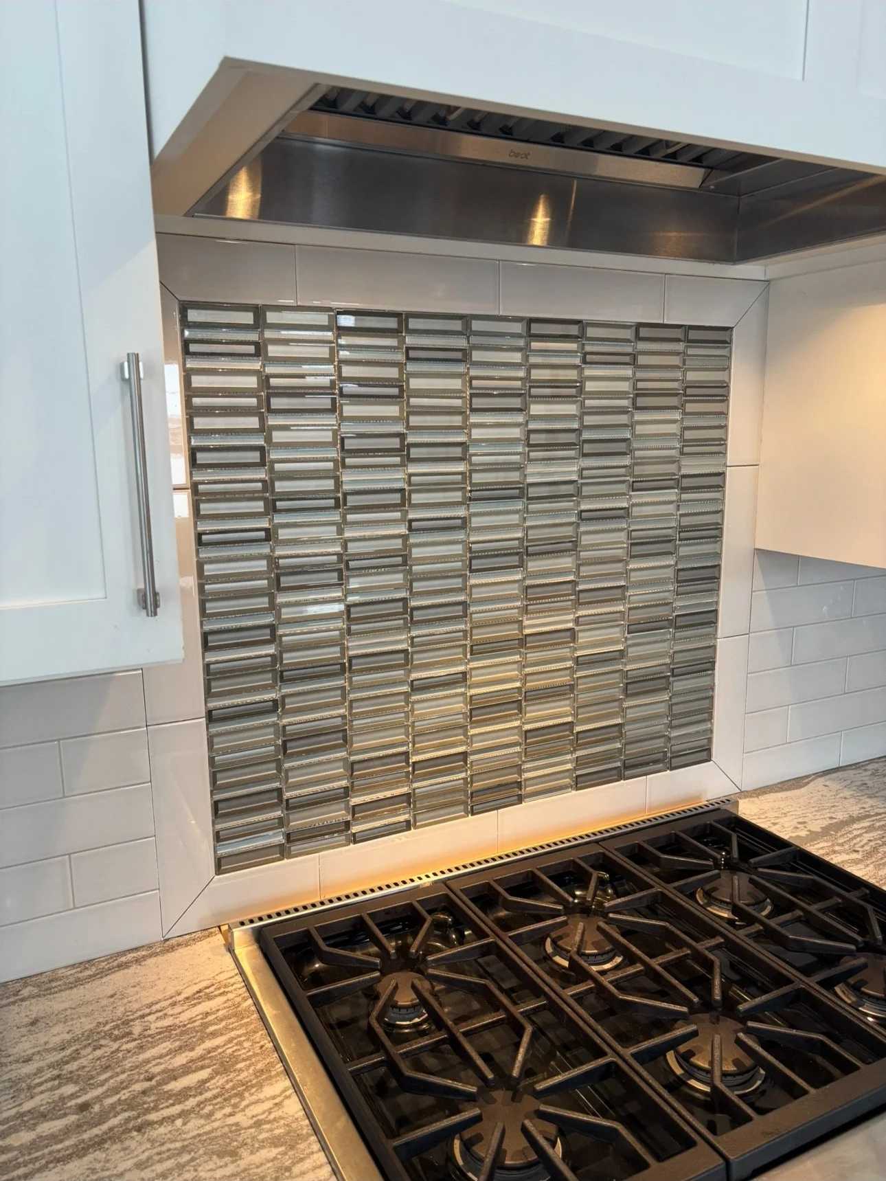 an updated kitchen backslash behind a gas stovetop