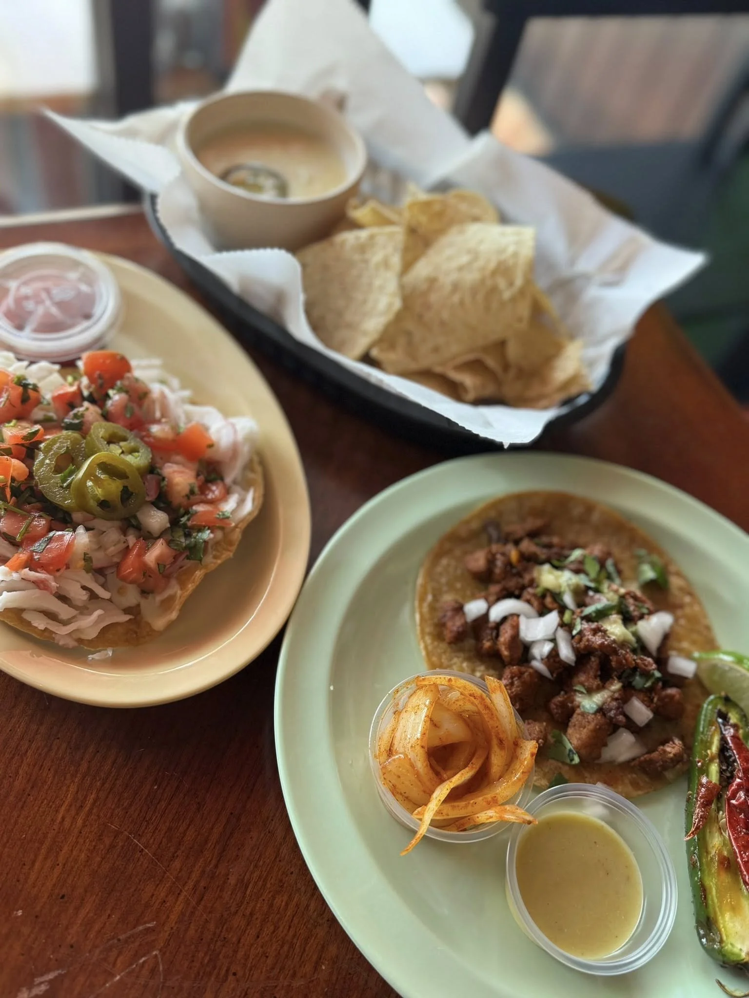 A plate of Mexican food with tacos, salsa, and grilled vegetables on a wooden table.