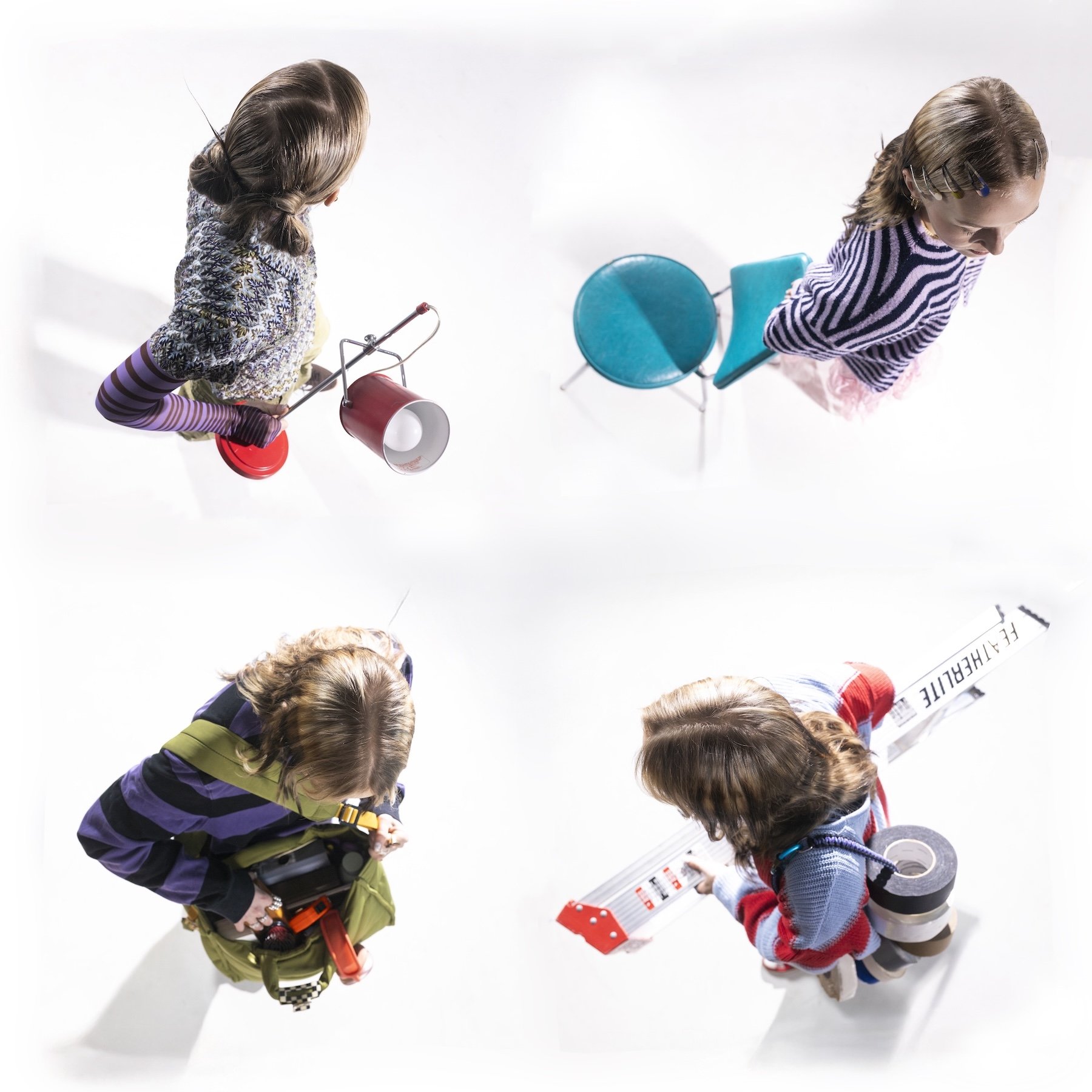Kids gathered together looking down, holding roll-up posters and various toys, with a white background.