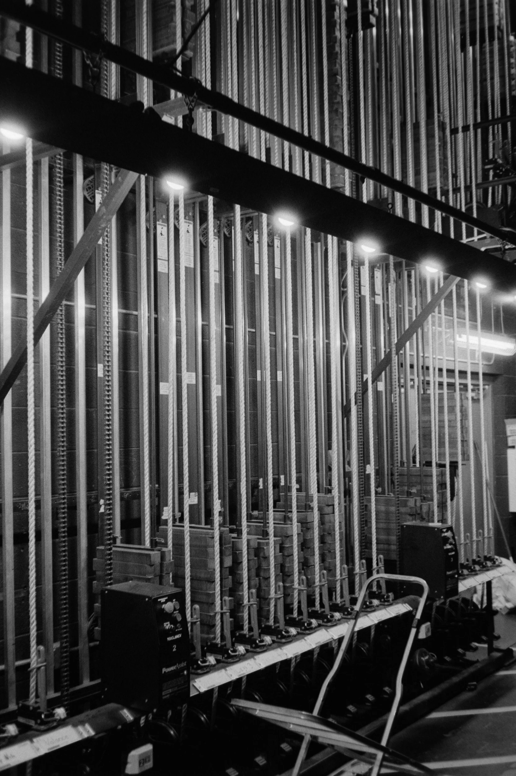 Store display with rows of power tools or equipment, unassembled, arranged vertically on shelves, with some control units and carts in the foreground.