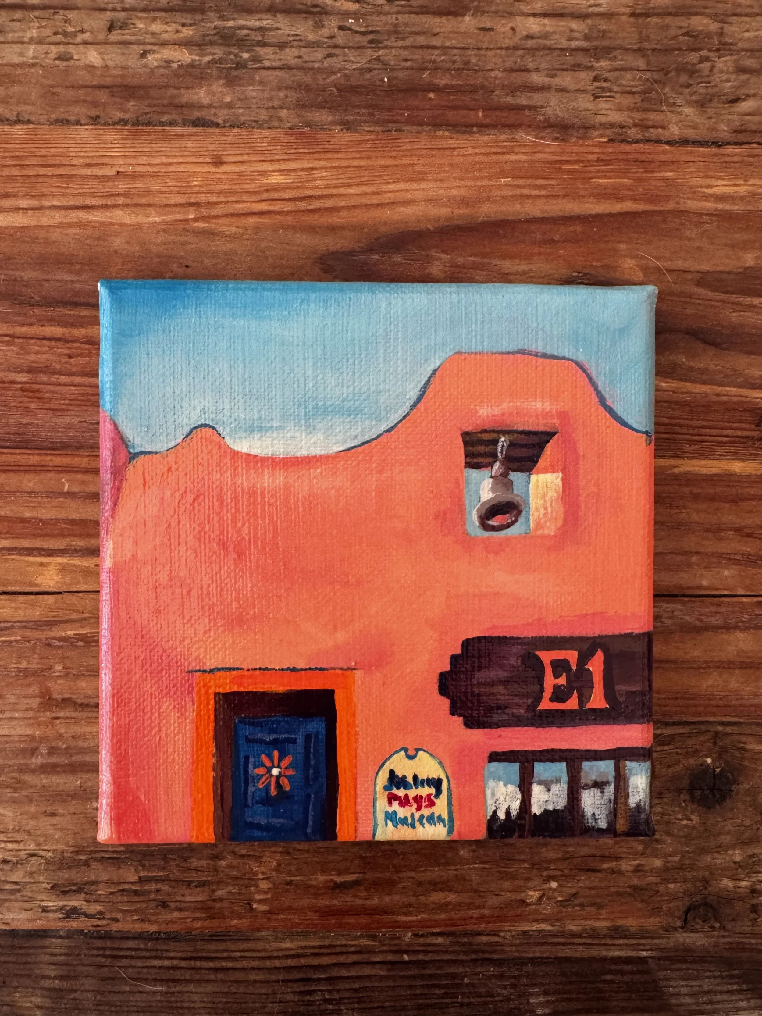 A painted canvas features a colorful scene with abstract elements and text that reads 'Holiday Pays Murder' on the lower part of the canvas.