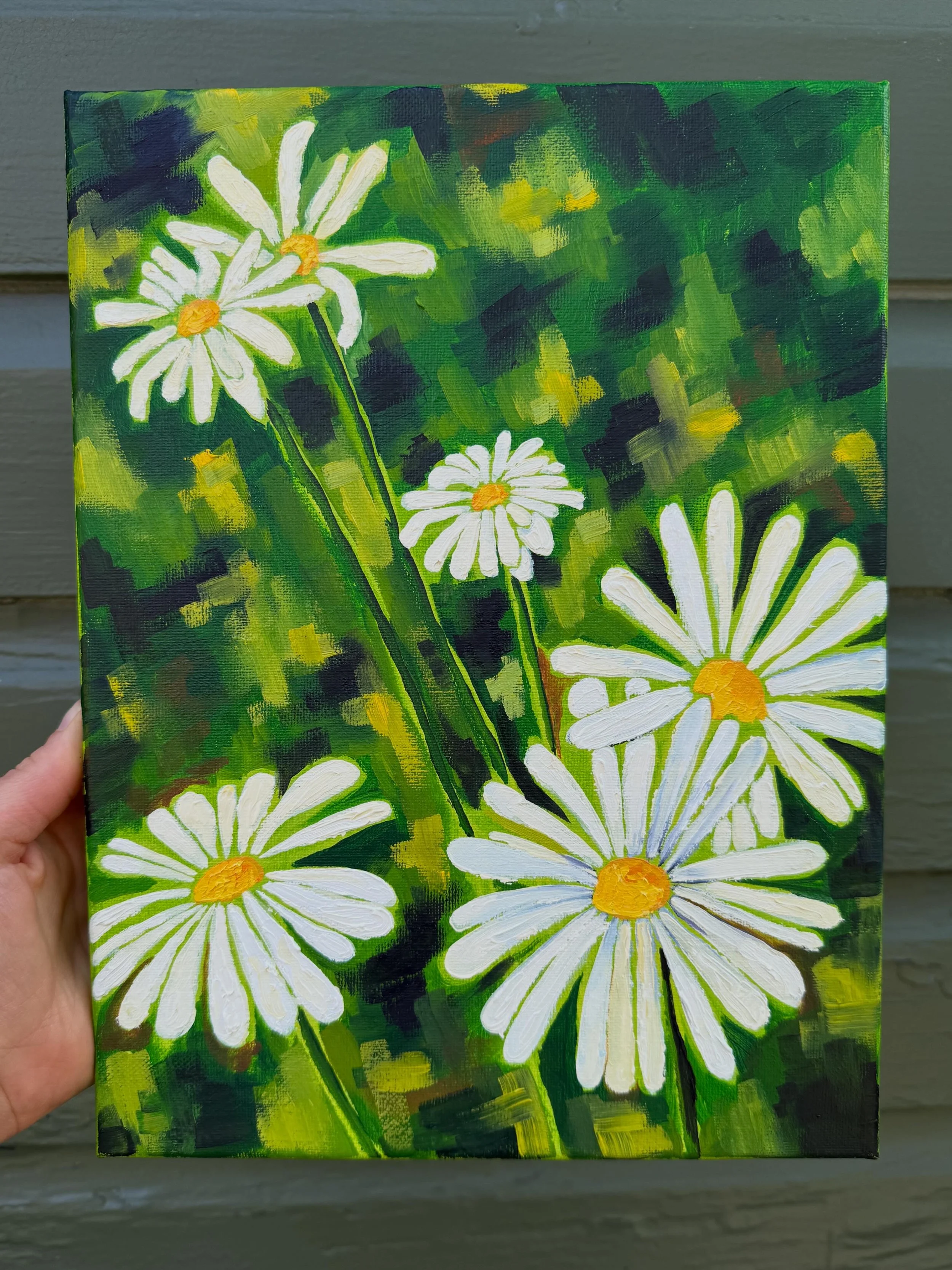 A small canvas painting of white daisies with yellow centers against a green, yellow, and dark background. The painting style appears to be impressionistic with visible brush strokes.