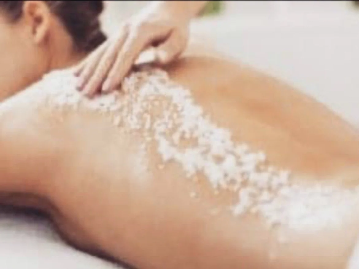 Person receiving a back exfoliation and massage lotion applied on their back.