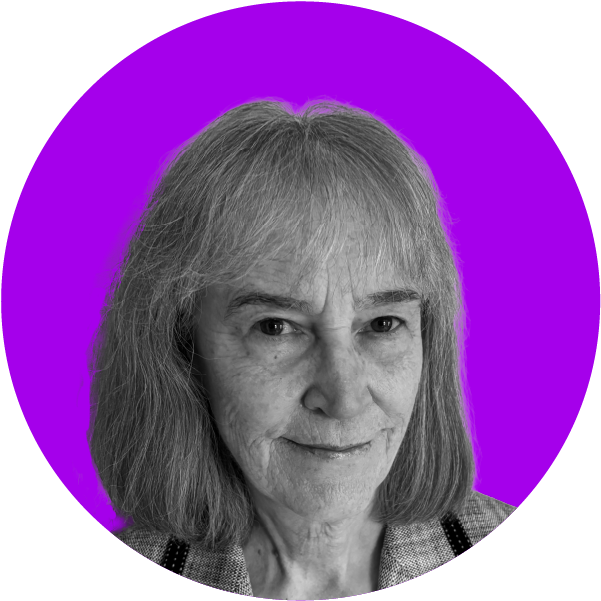 Close-up of an older woman with shoulder-length gray hair and a slight smile, set against a purple background.