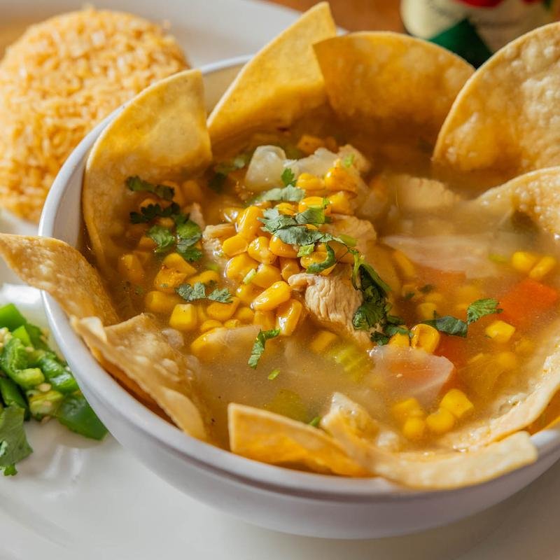 Bowl of chicken tortilla soup garnished with cilantro and served with tortilla chips
