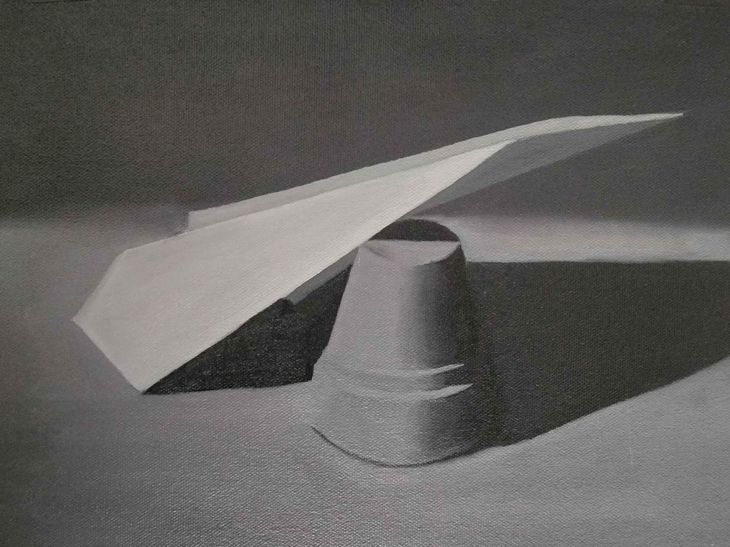 Close-up of a modern decorative sculpture with sleek, smooth, elongated shapes in shades of white and black, set against a textured gray surface.