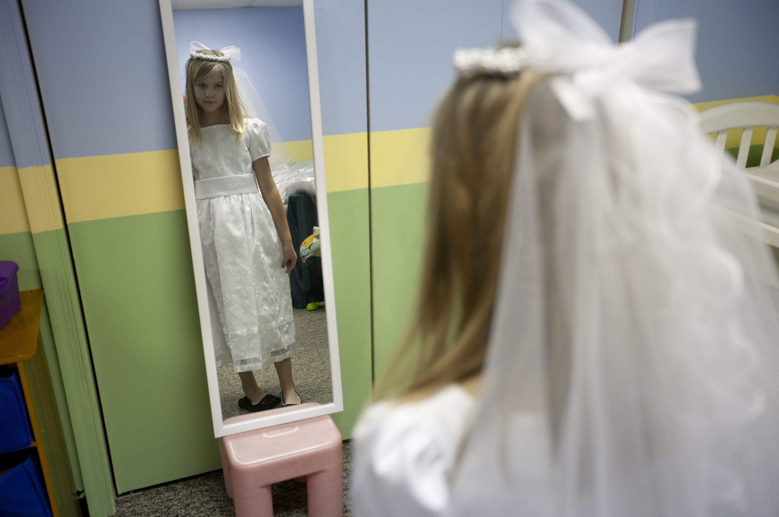Ava Rose Smith, 8, of Linglestown, Pa., looks at herself in a first communion dress at St. Patrick Cathedral in Harrisburg, Pa.