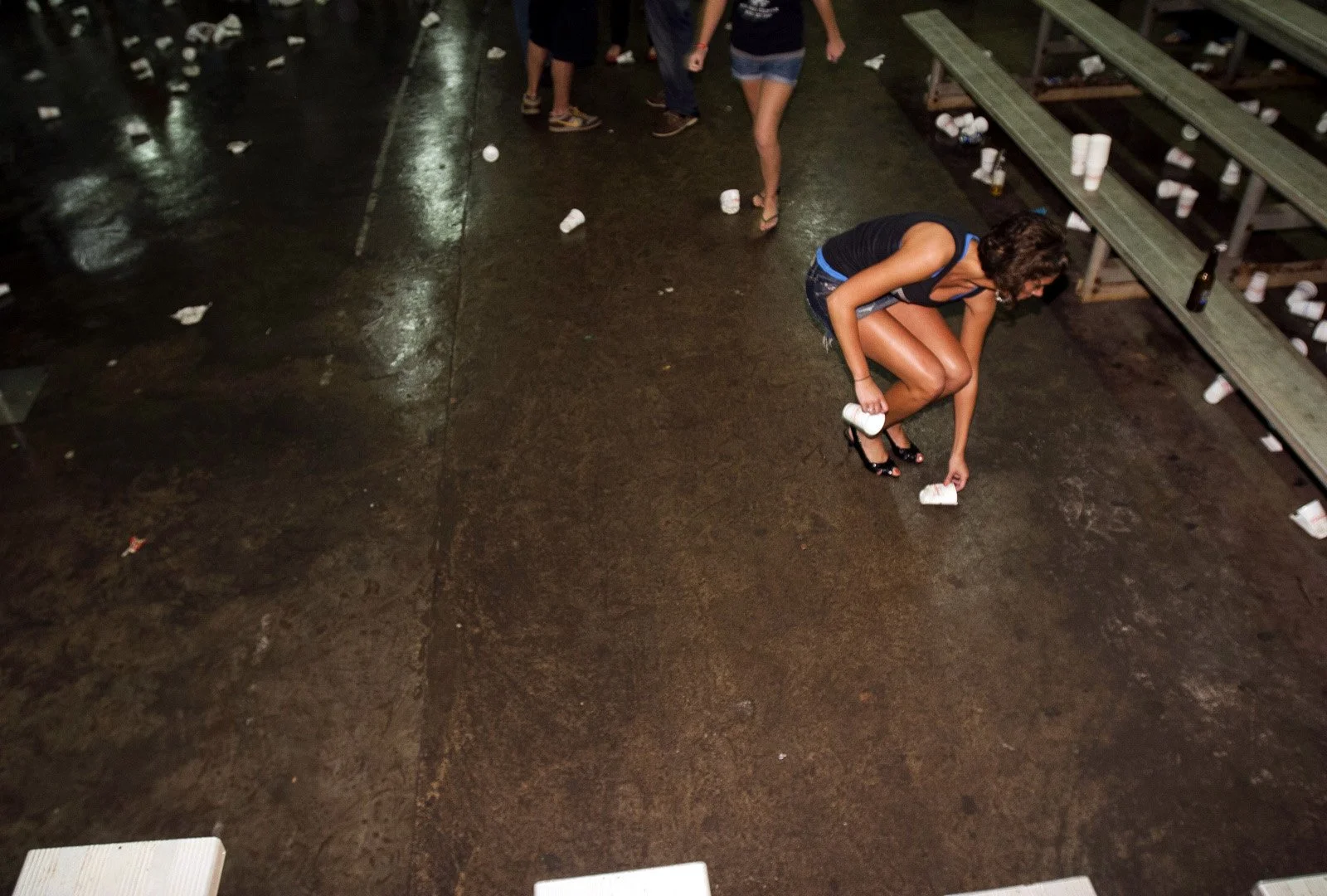 Amanda Helman, a Sigma Chi fraternity sweetheart, cleans up used cups in heels after an event for the fraternity in Bowling Green, Ky.