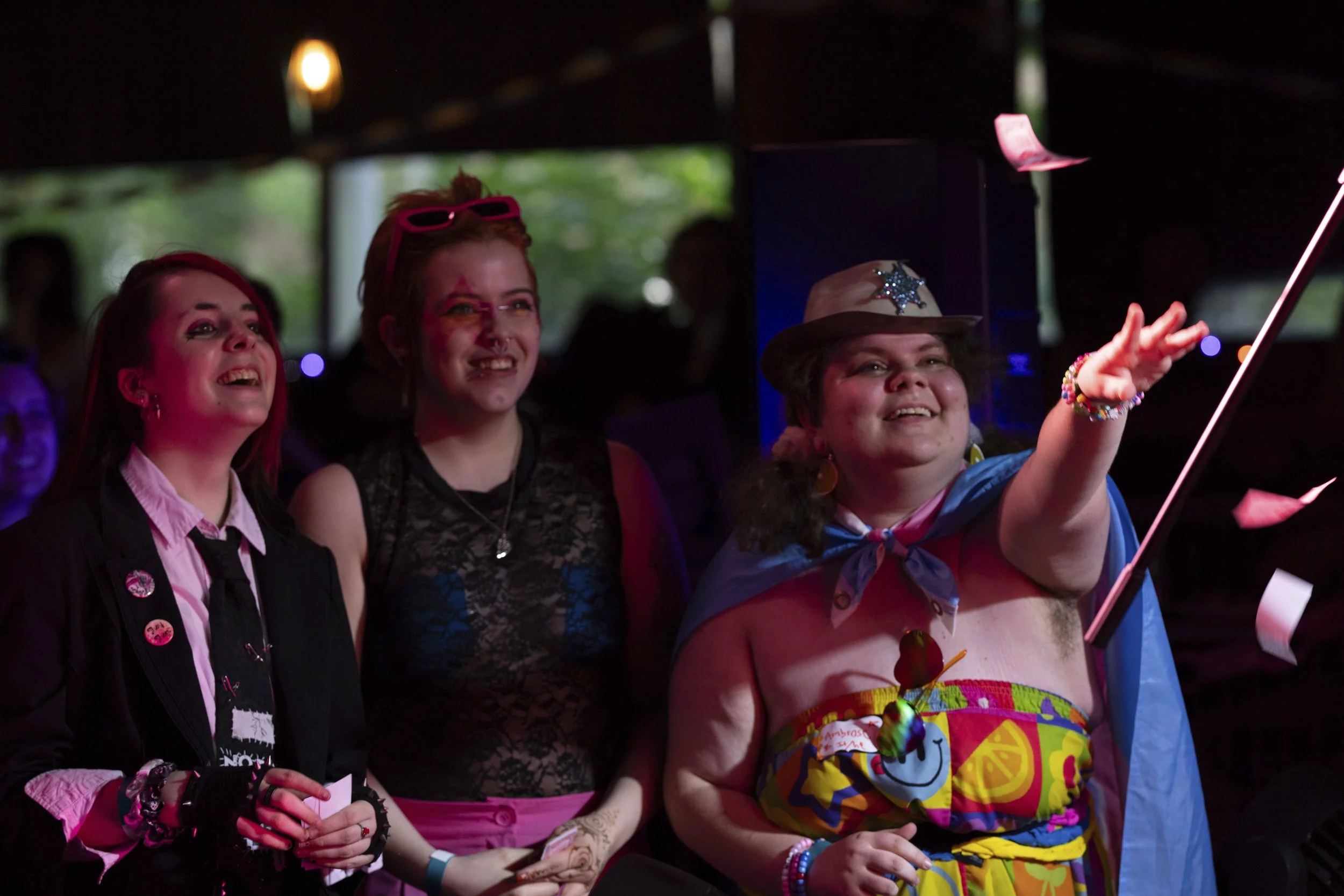 From left, June Arney and Caspian Brooks watch as Ambrose throws faux money on stage as a drag king performs during a “Pink Pony Prom” held to celebrate teen and young adult members of the LGBTQ+ community on Friday, May 30, 2025, in Portland, Ore.