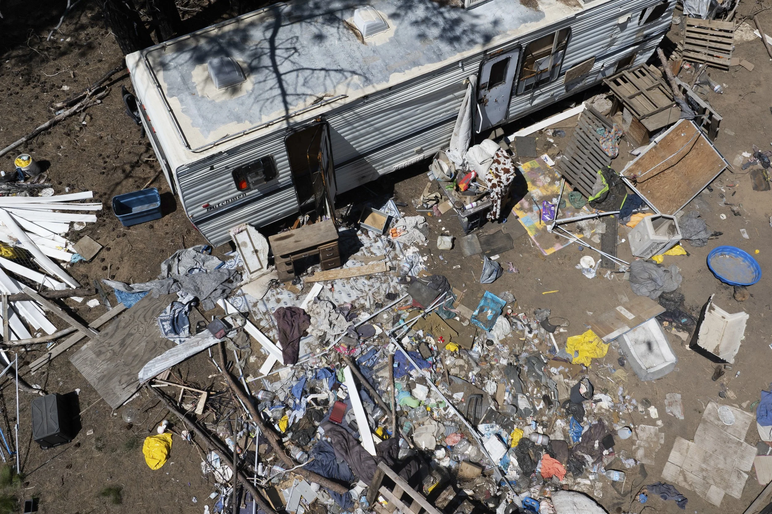 Debris lies scattered around a trailer at a homeless encampment in Deschutes National Forest, Thursday, May 1, 2025, near Bend, Ore.